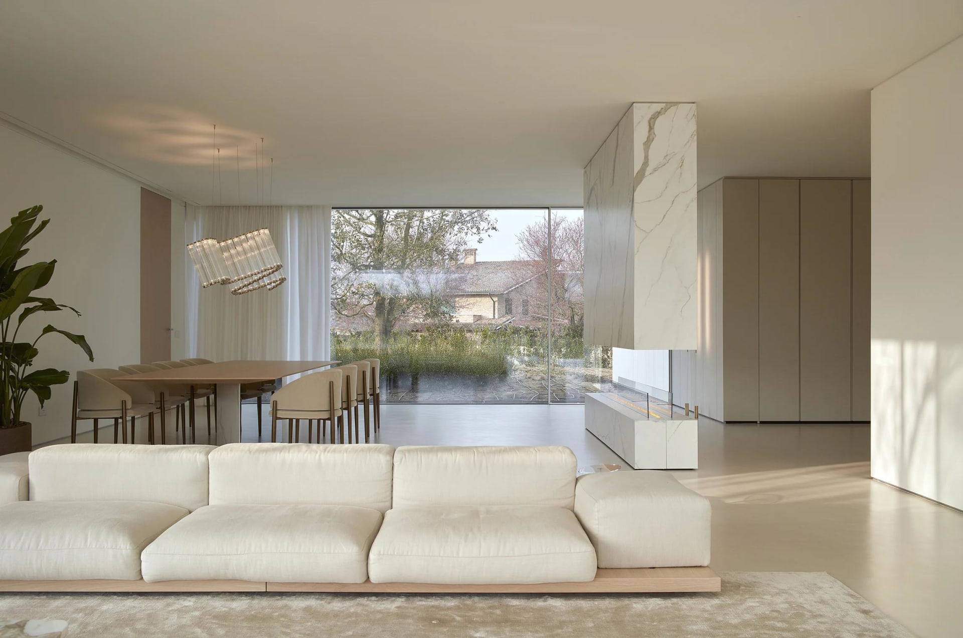 Modern living room featuring a minimalist design with marble elements and a large glass window.