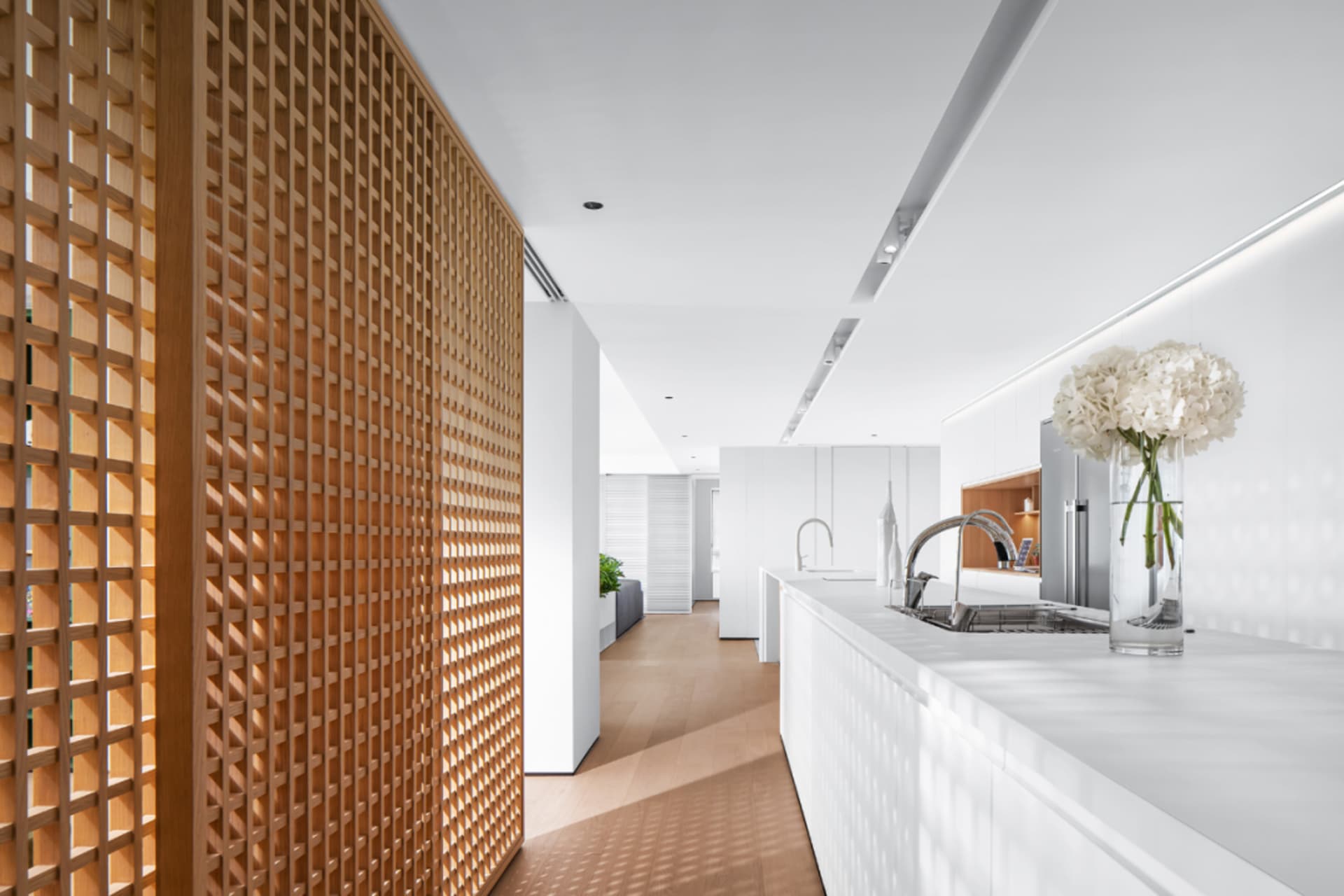A modern minimalist kitchen featuring white marble countertops and wooden accents.