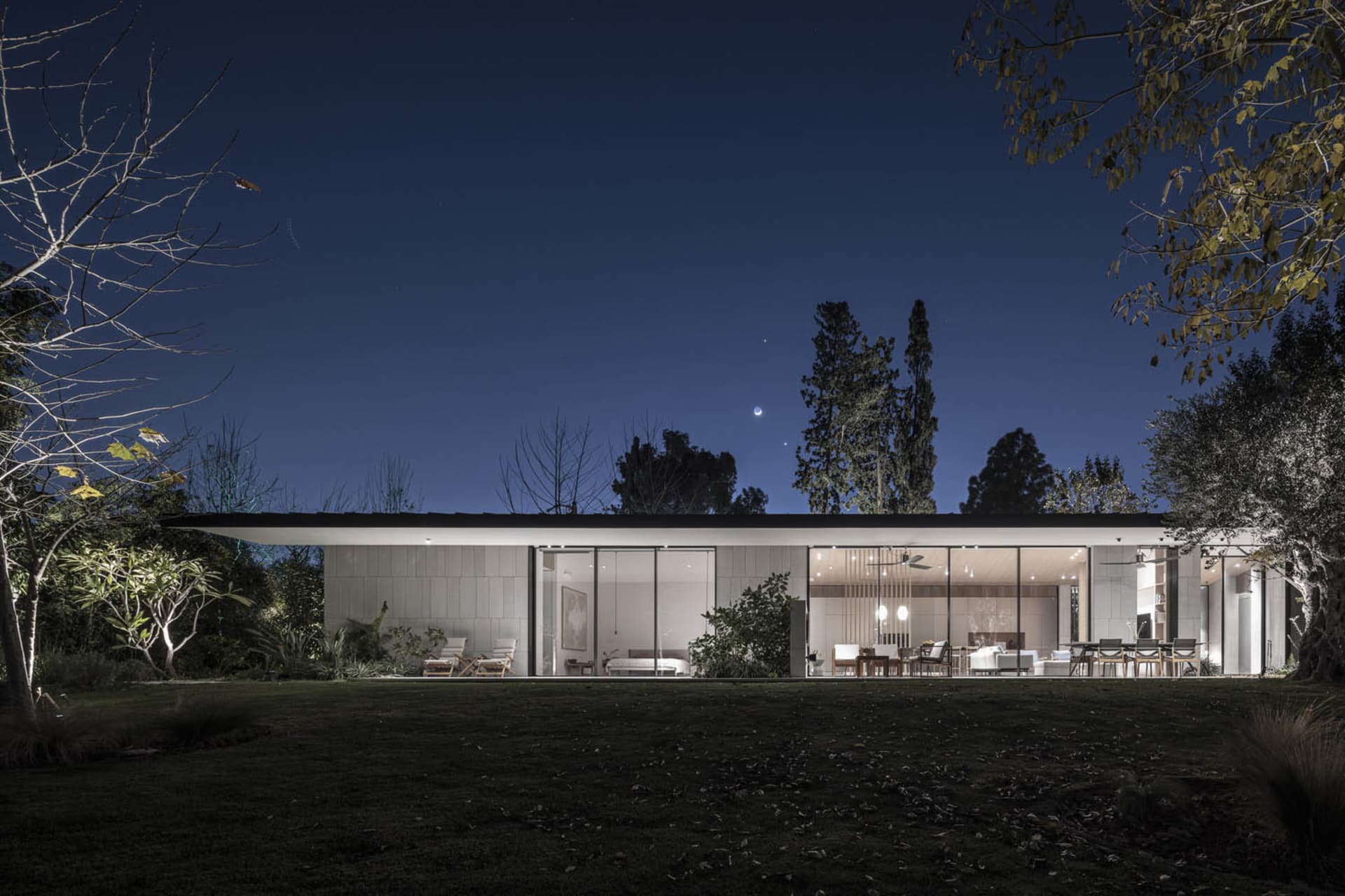 Modern residential exterior illuminated at night with a focus on concrete and glass surfaces.