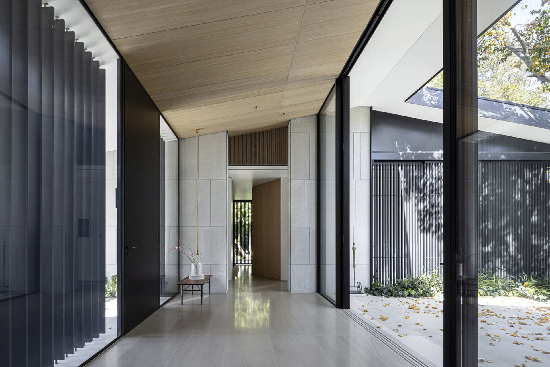Modern entrance hall with concrete walls, glass storefront doors, and wooden ceiling beams.