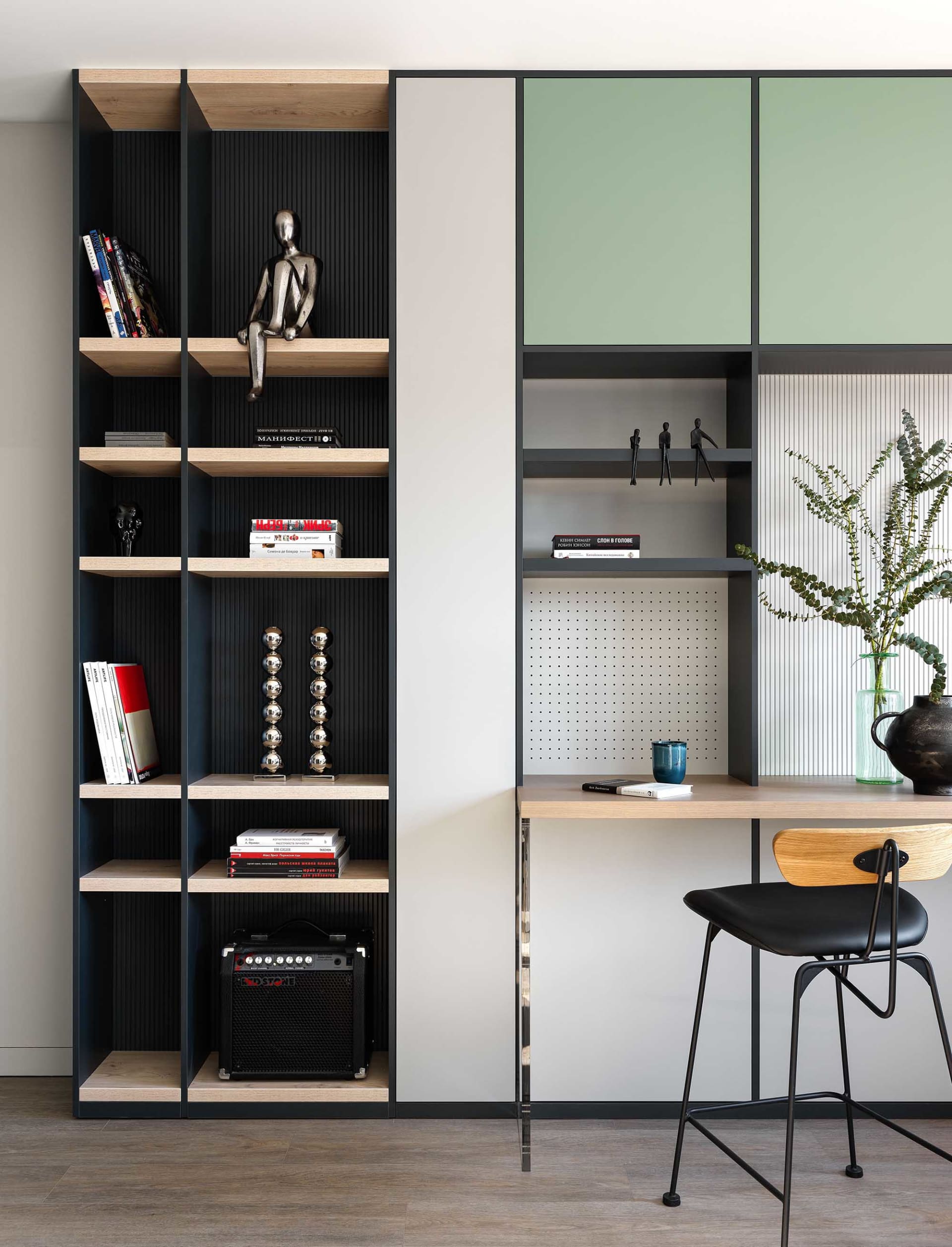 A modern industrial office space featuring metal shelving, wooden desks, and glass partitions.