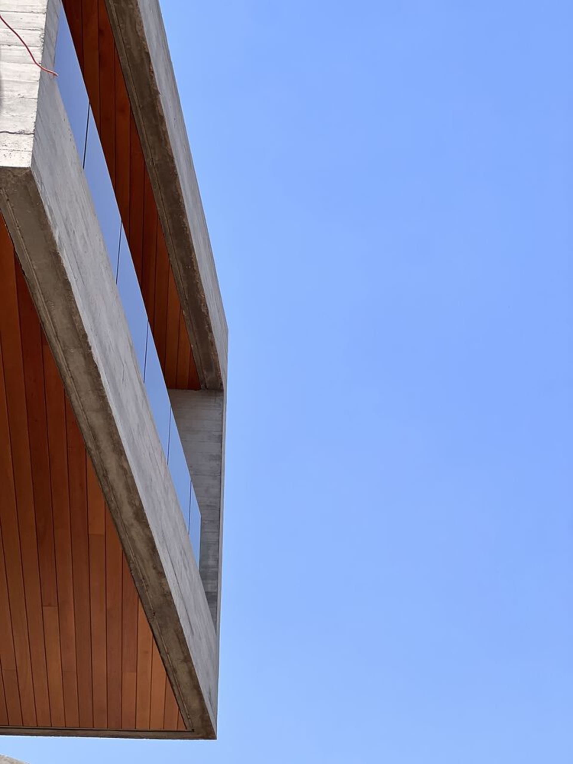 Concrete exterior of a modern building against a clear blue sky.