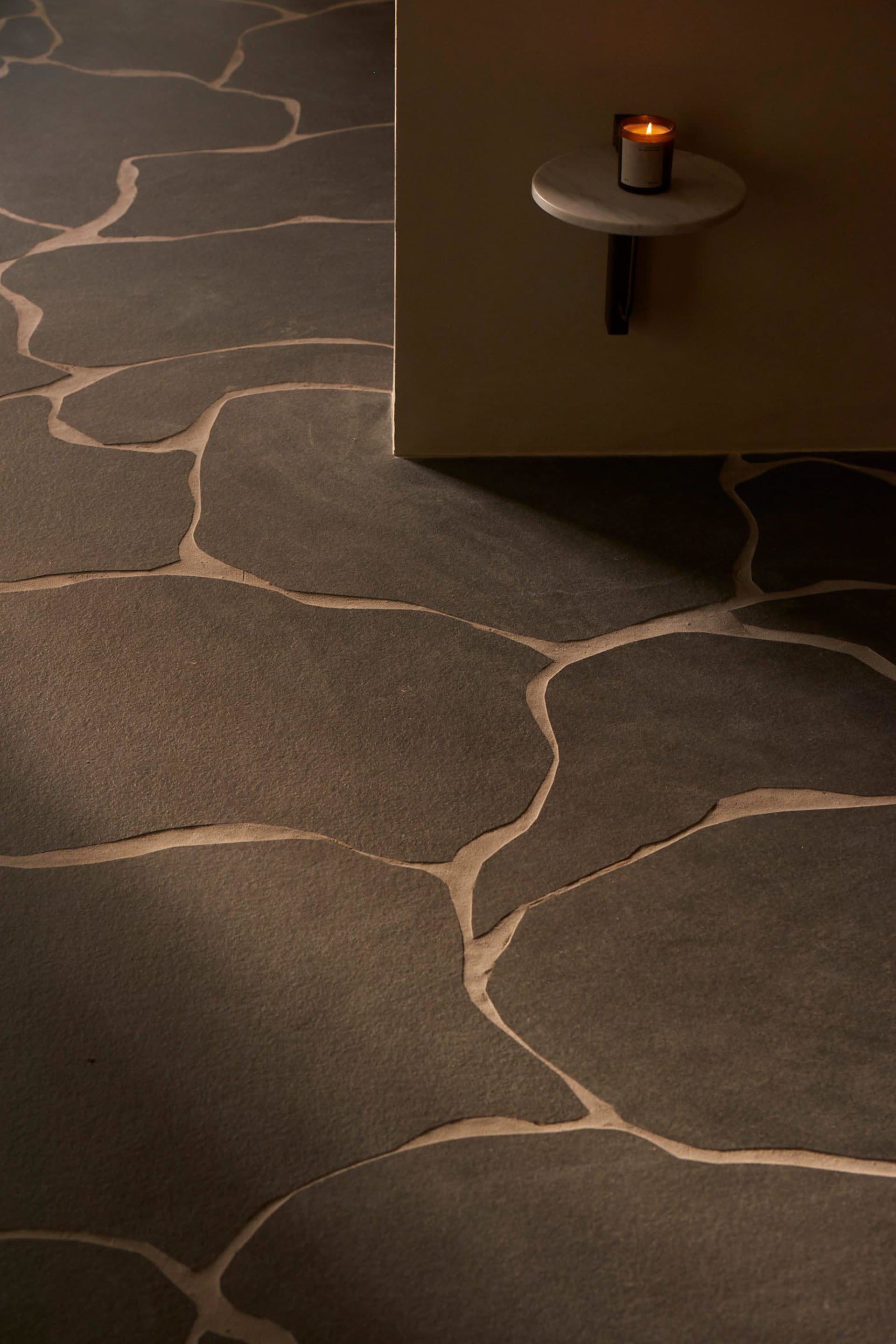 A modern interior space featuring stone floor tiles with a natural, irregular pattern.