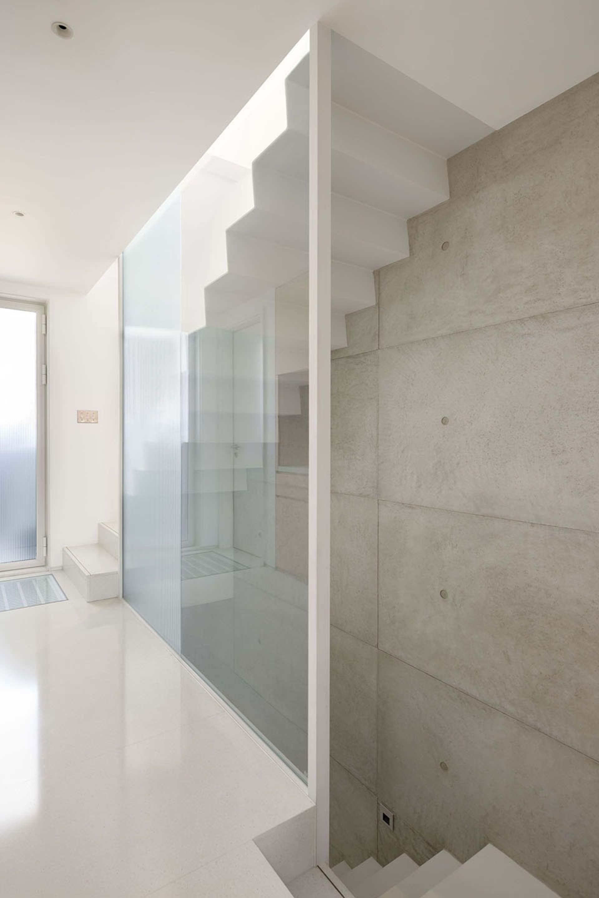 Minimalist interior design featuring a modern staircase with concrete and glass elements