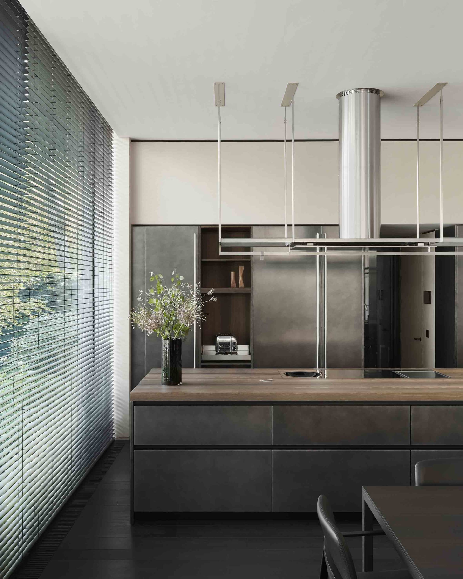 Modern residential kitchen with metal cabinets and wooden countertop.