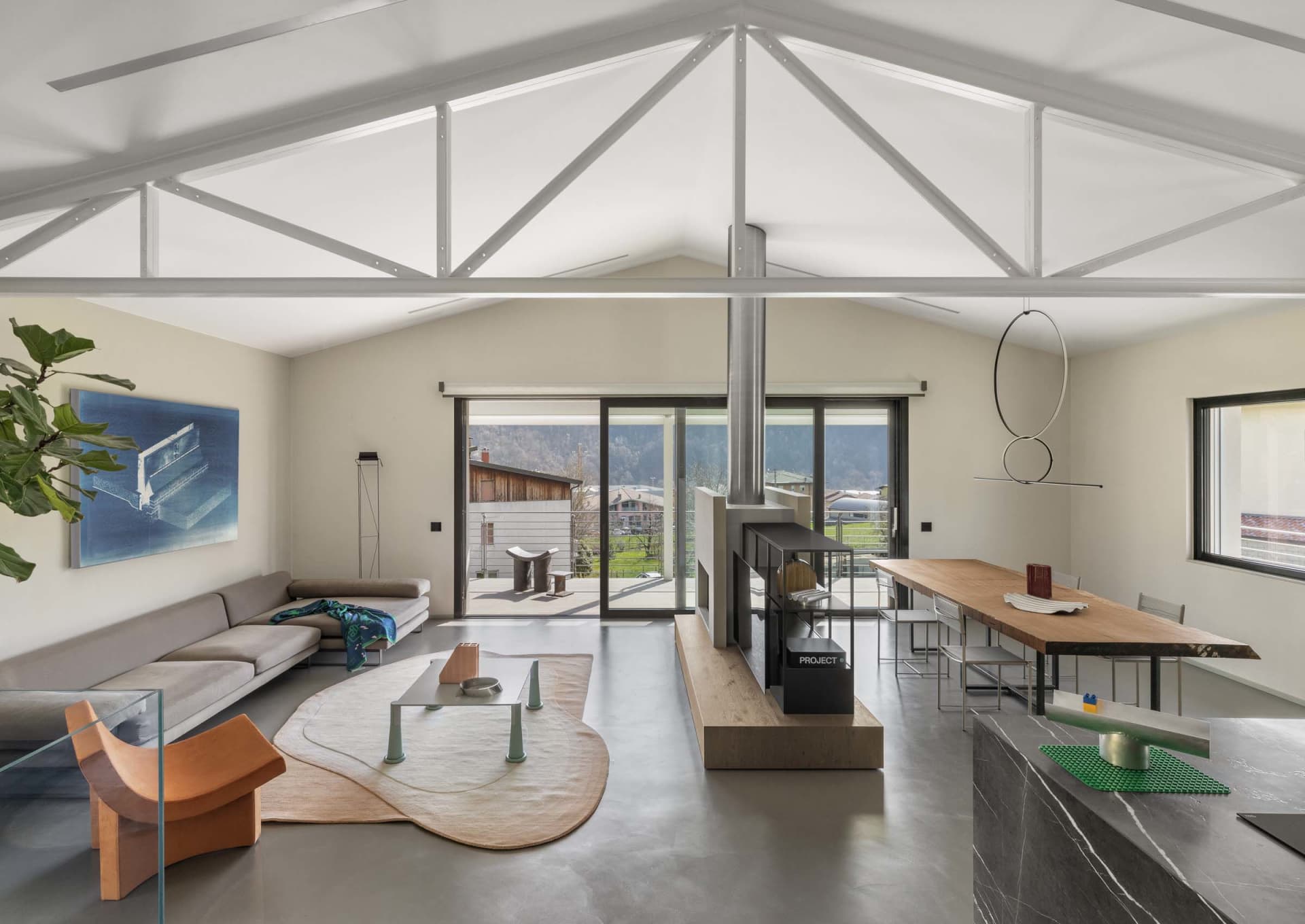 Modern industrial living room with concrete walls and floor, featuring minimalist furniture and large windows.