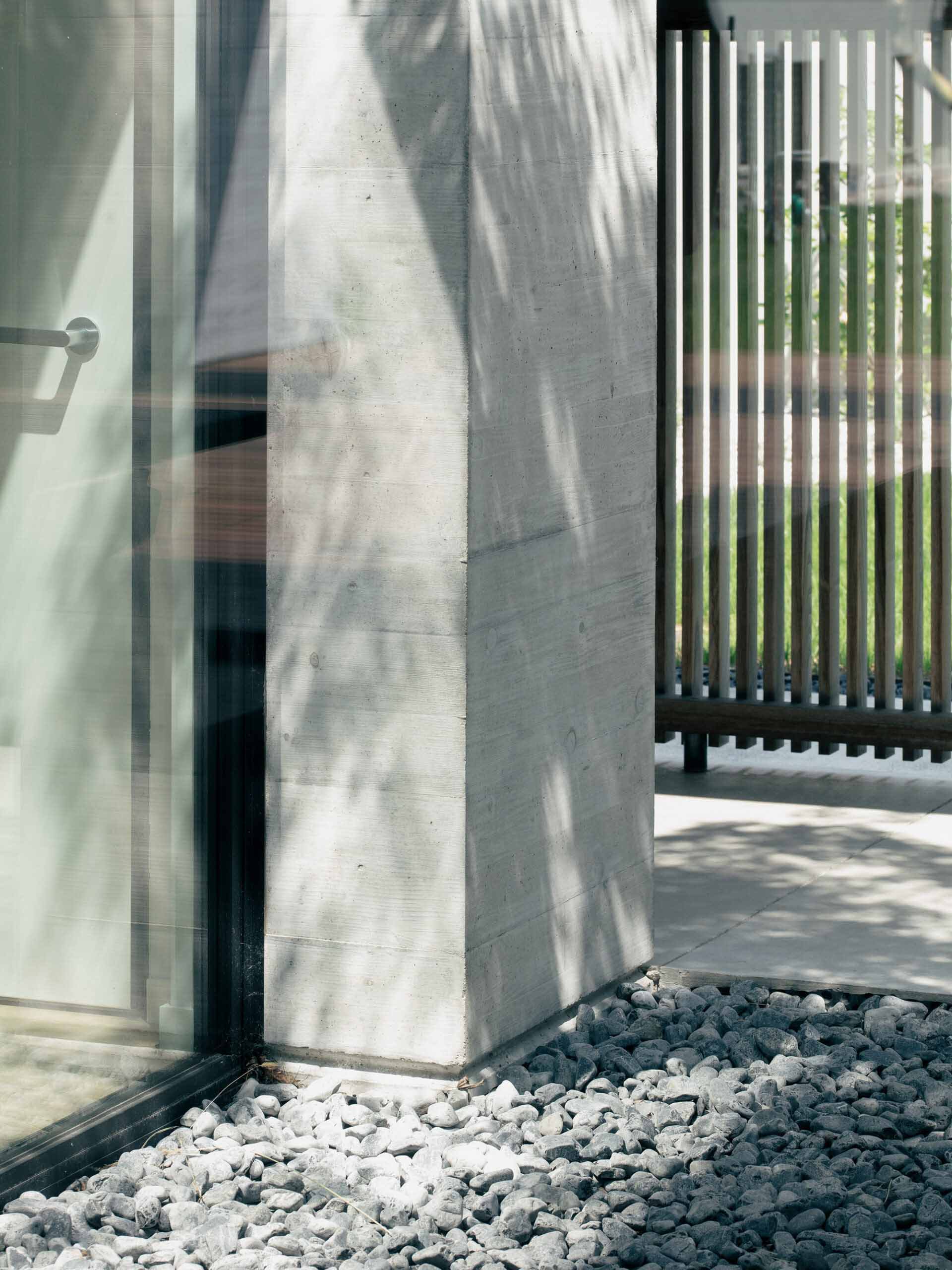 A minimalist entryway featuring smooth, dark concrete surfaces, with a combination of dark and lighter shades, creating a sle