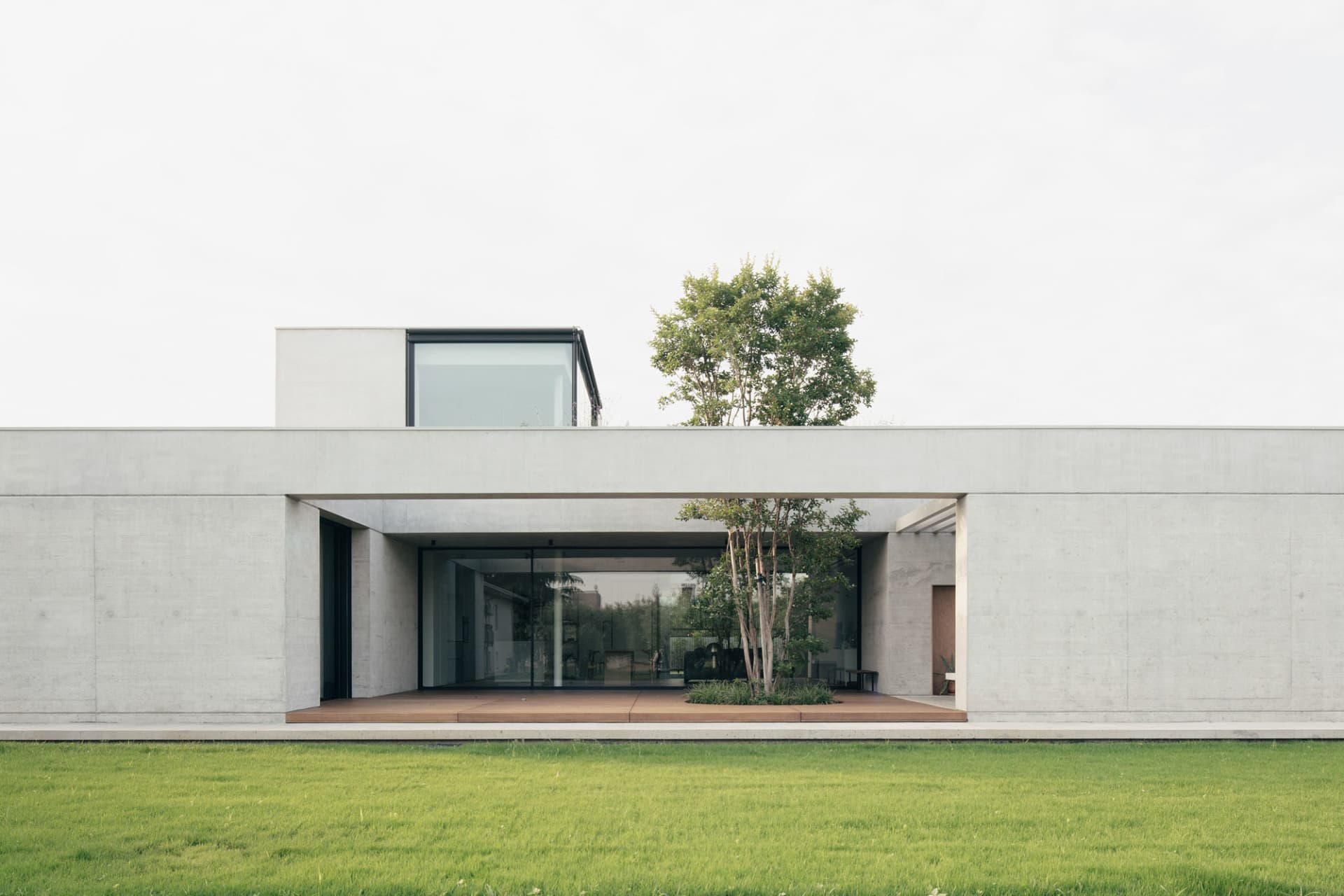 Modern house exterior featuring cement walls and a glass window.