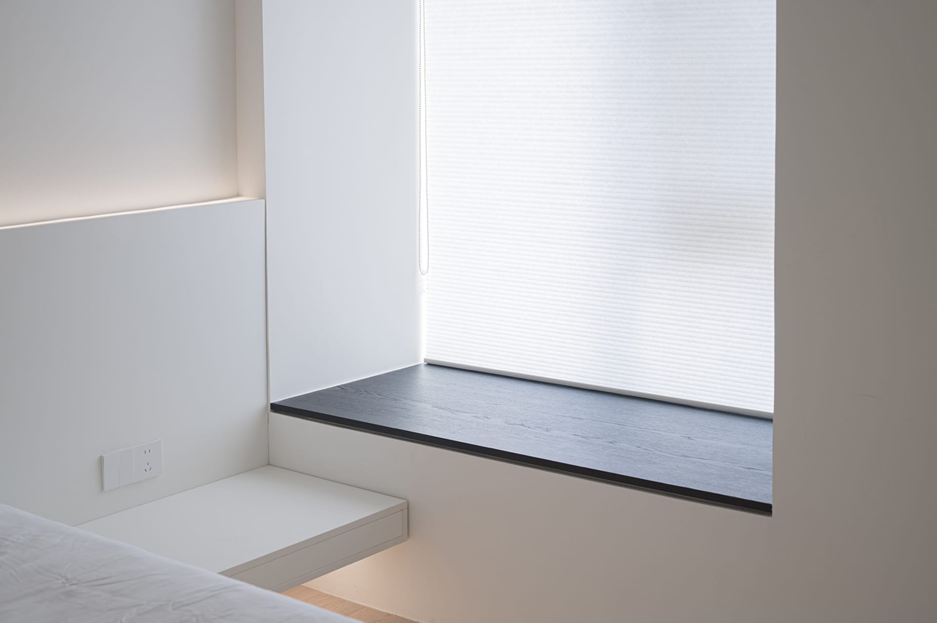 Minimalist bedroom featuring a floating shelf against a white wall.