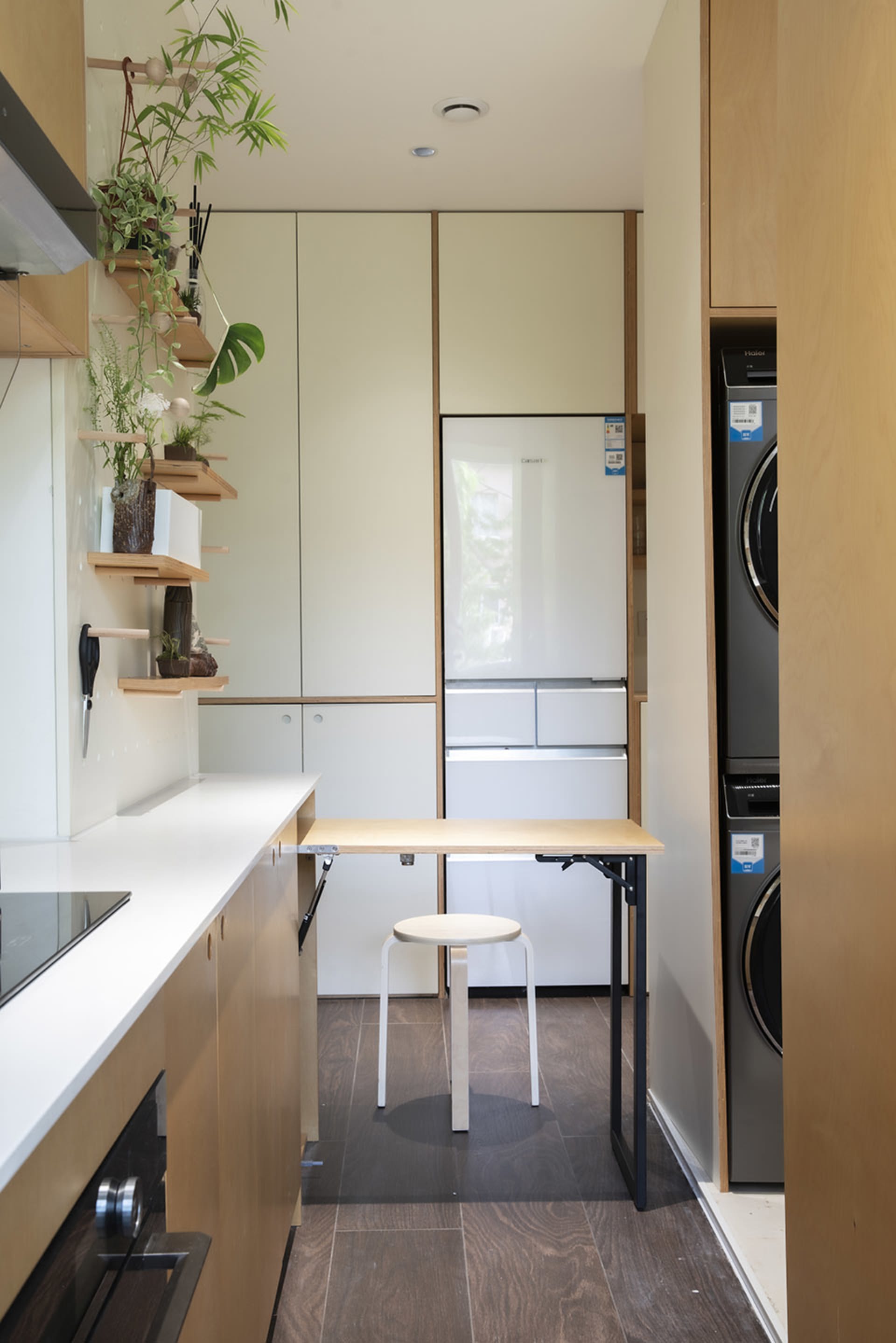 A minimalist kitchen with white laminate countertops, wooden cabinets, and metal appliances.