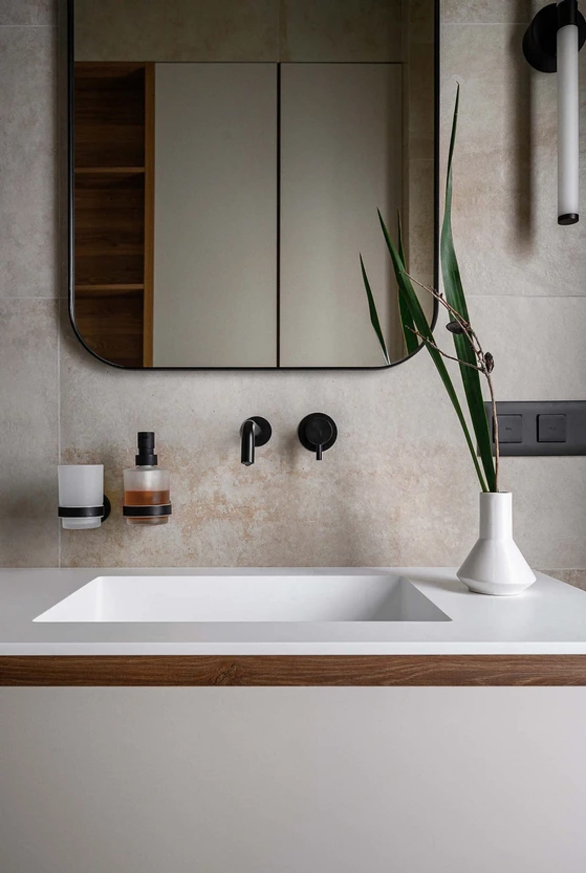 A modern bathroom featuring a floating sink with a white basin and a wooden countertop, set against a concrete and wood wall