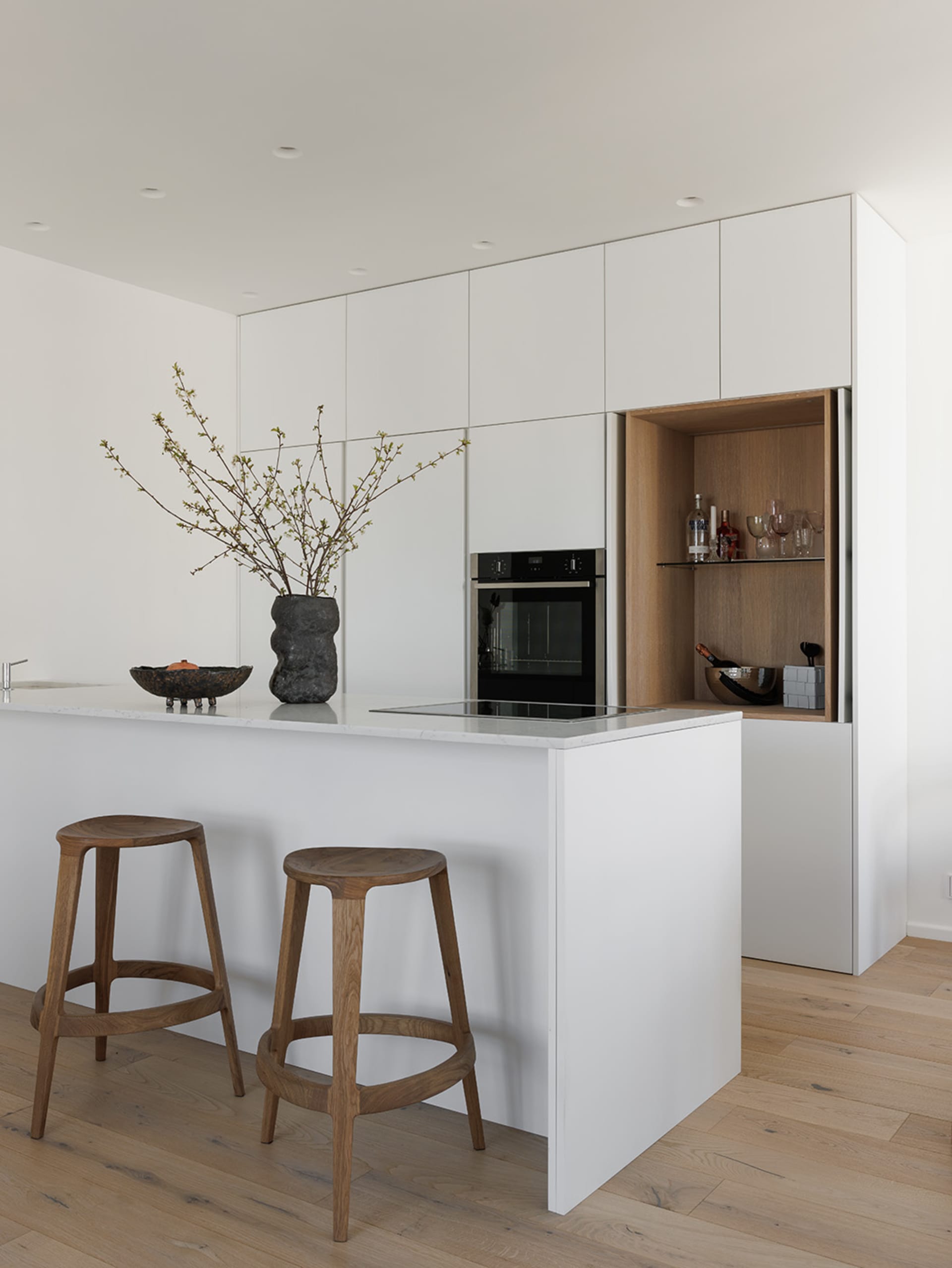Modern white kitchen with minimalist design and wooden stools