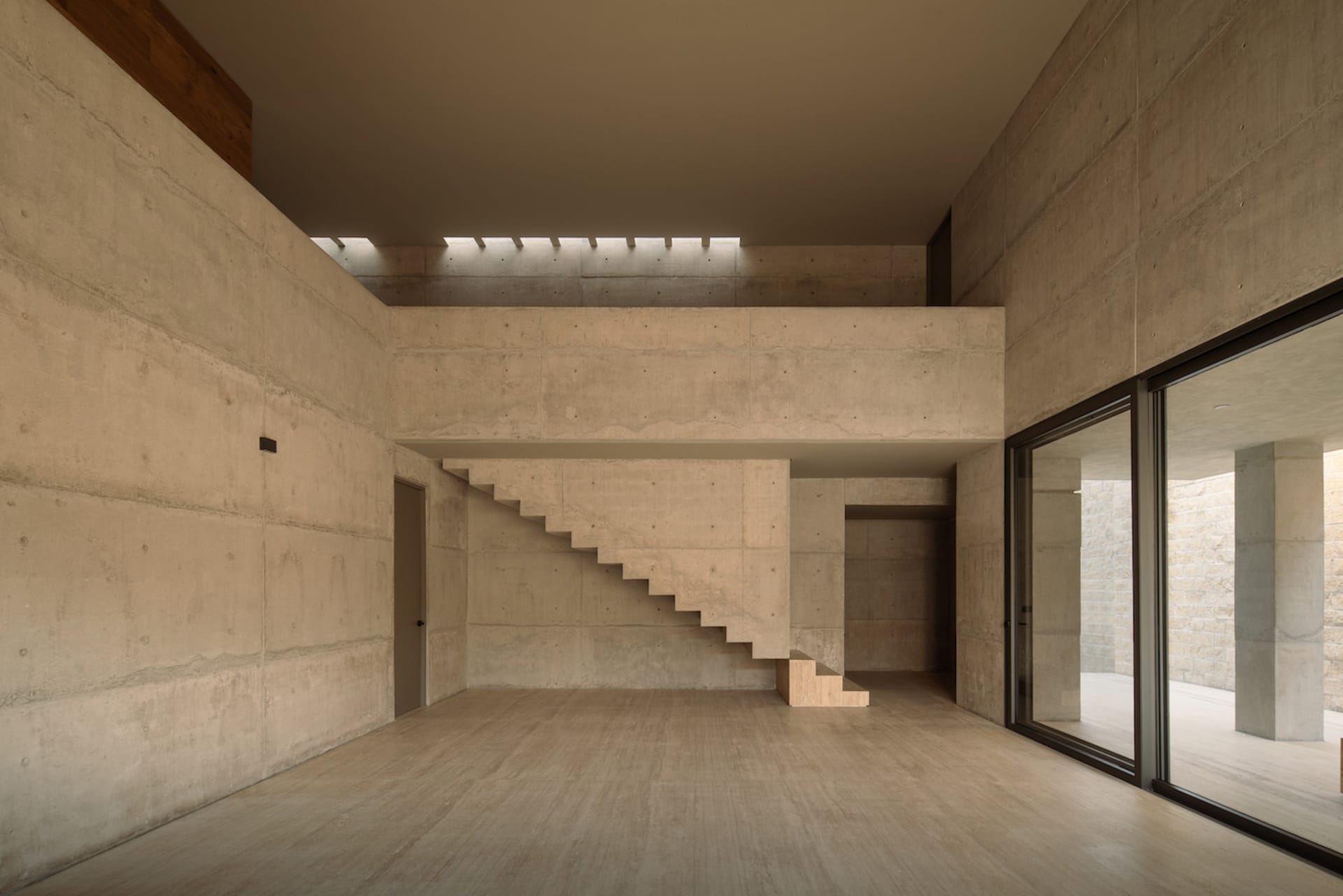 A minimalist interior design featuring a concrete staircase and walls in a spacious room.