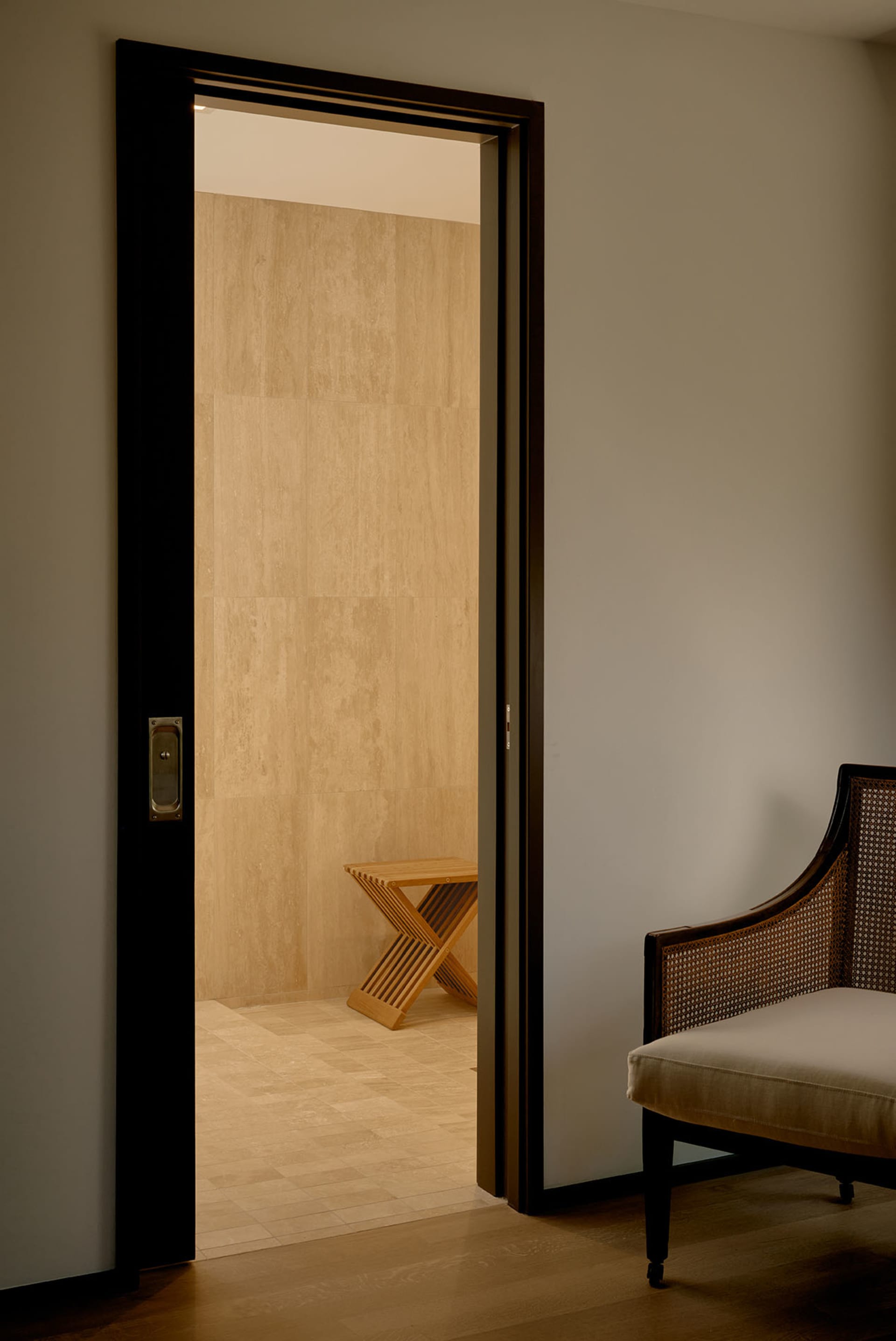 A minimalist doorway leads into a room with a wooden table.