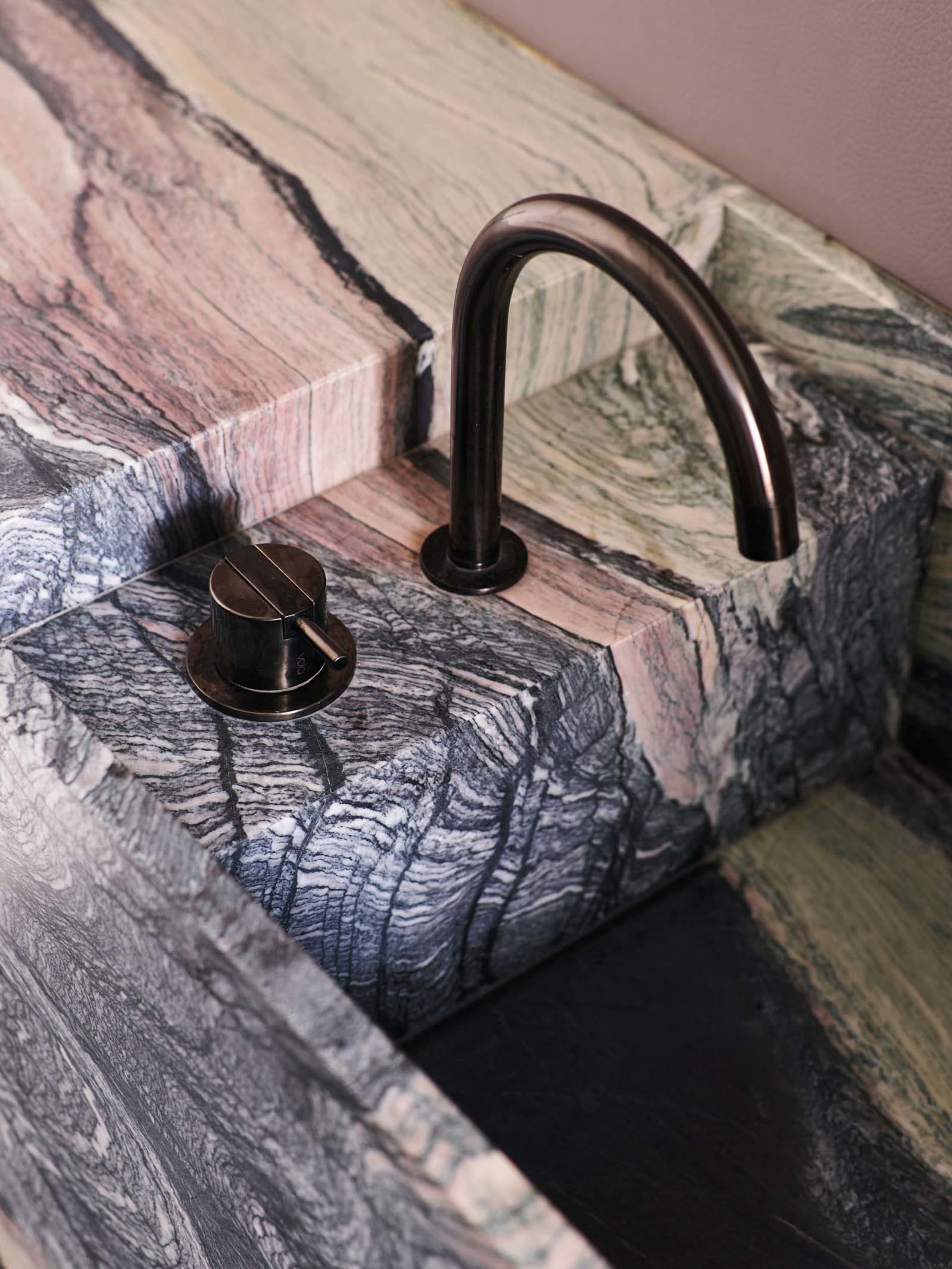 Modern bathroom designed with marble materials, featuring a sleek faucet and styled fixtures.