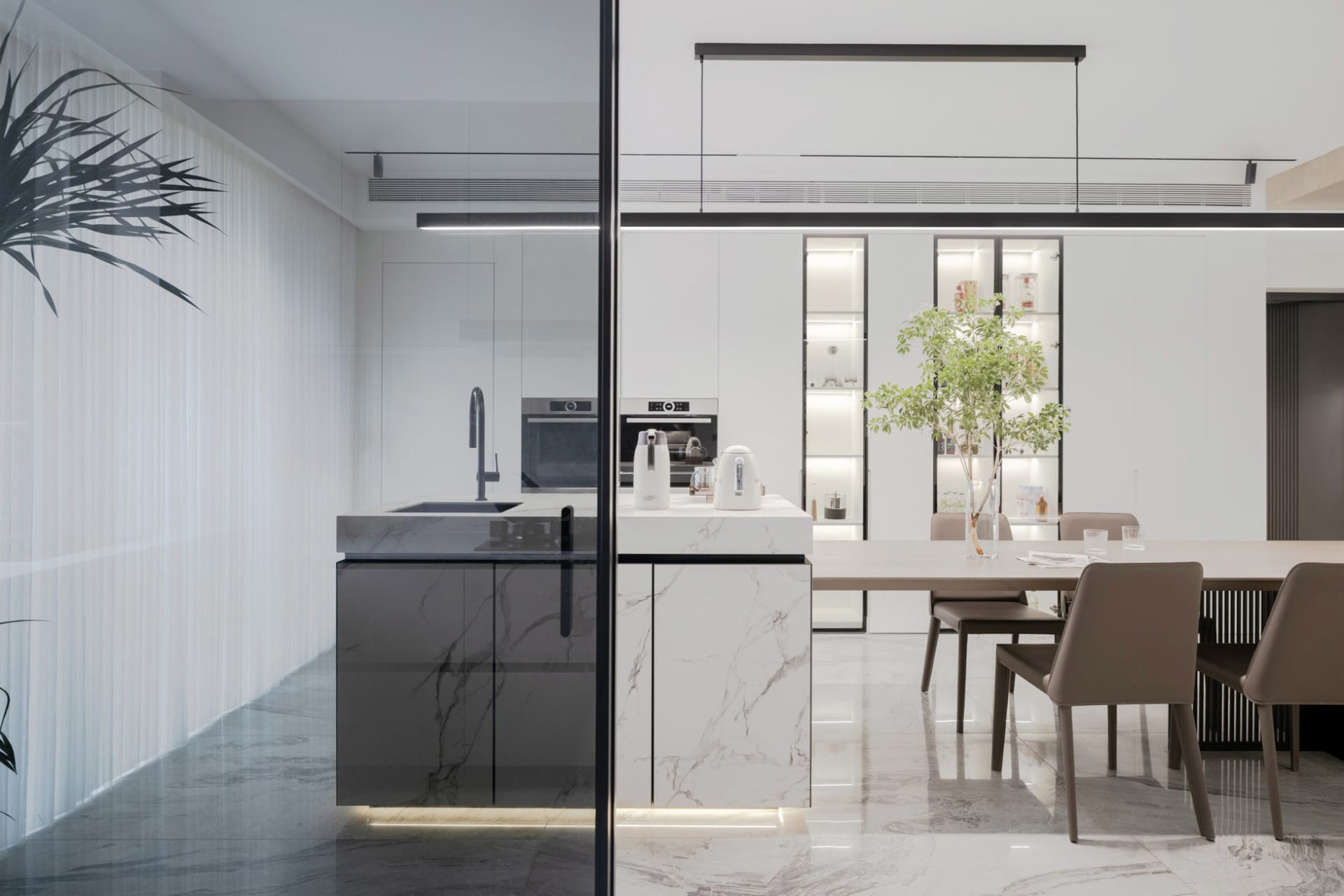 Modern residential kitchen featuring marble countertops and glass cabinets.