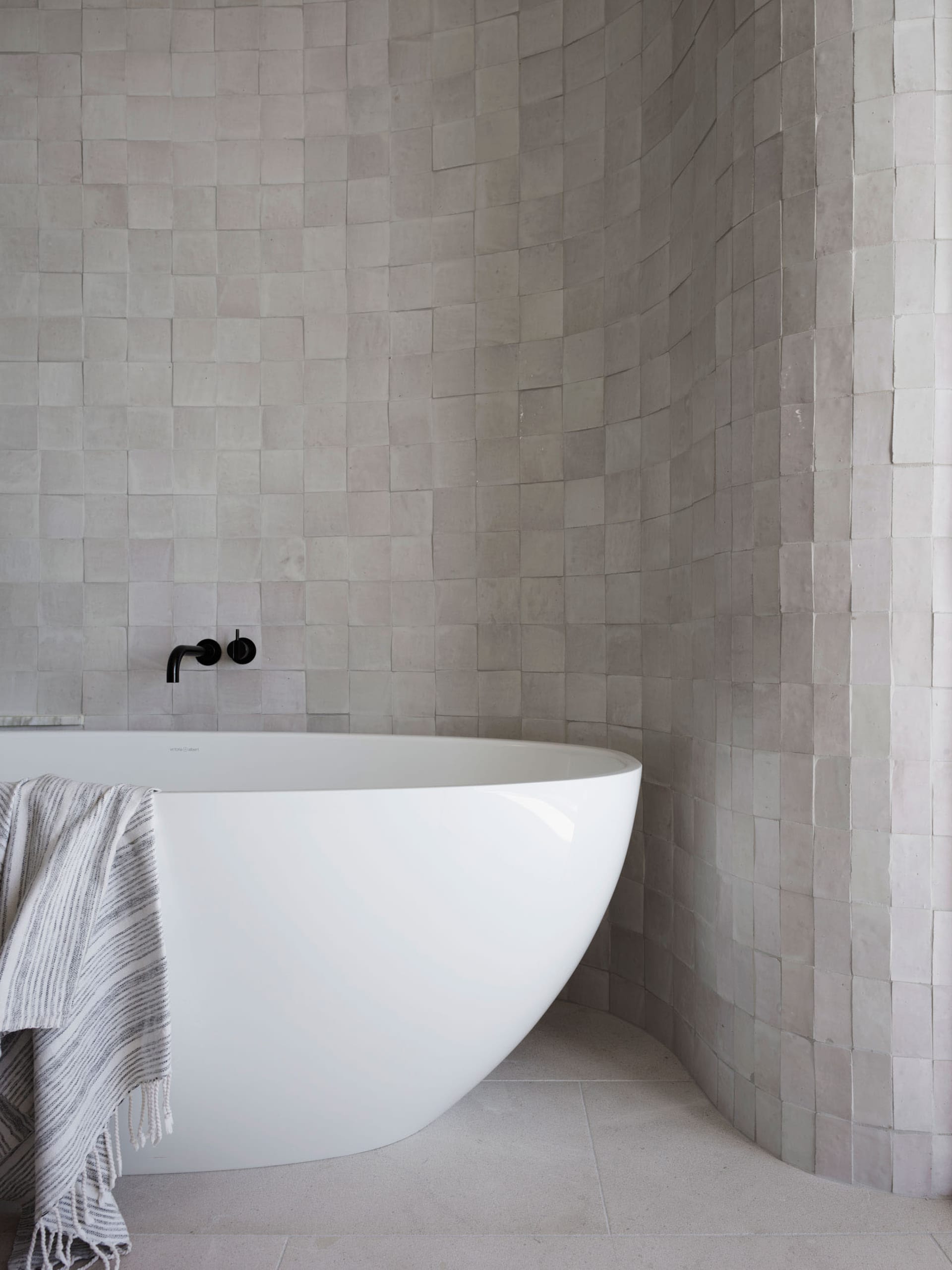 Modern minimalist bathroom with concrete tiles and a white bathtub.