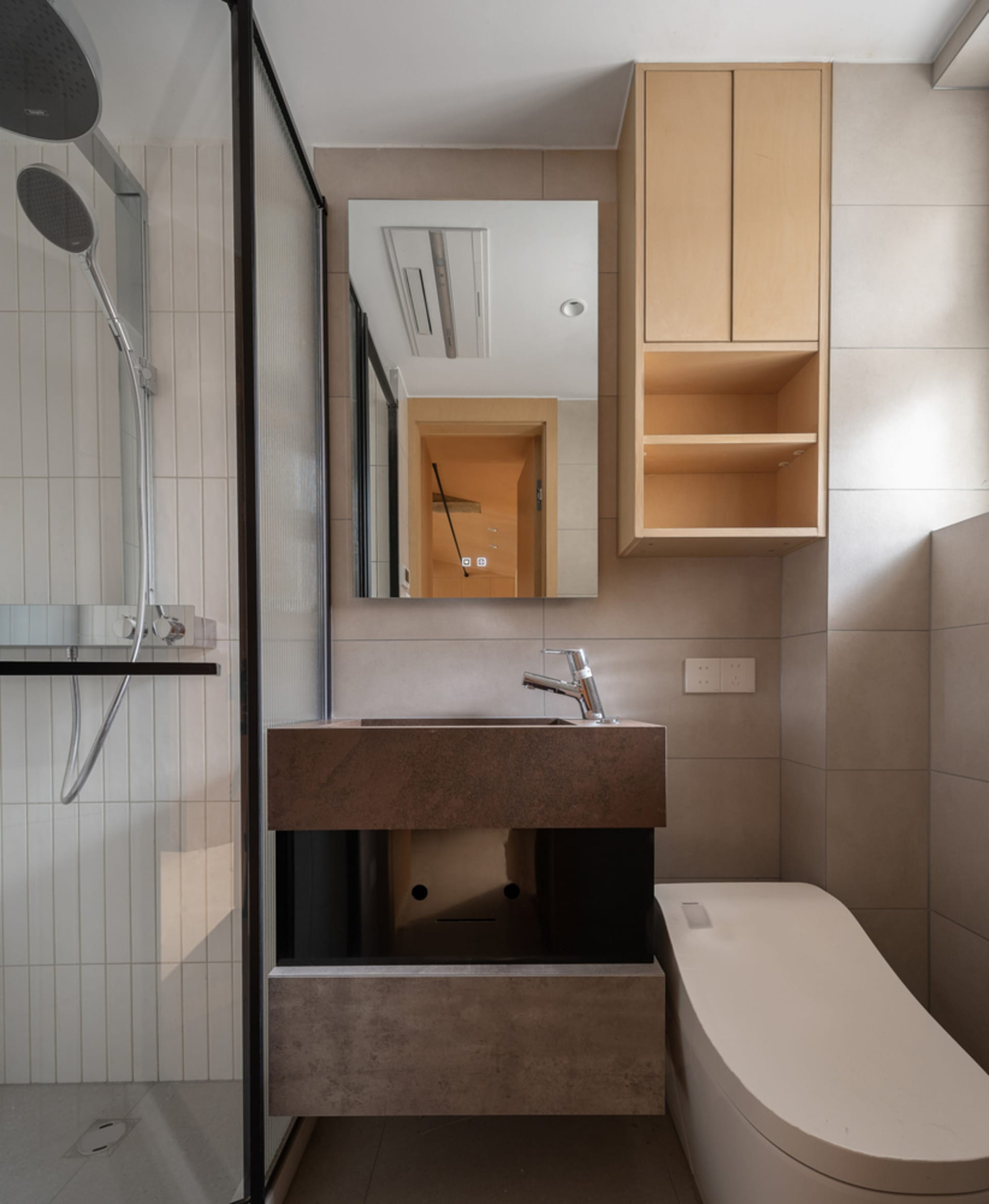 A minimalist bathroom features concrete countertops and a wooden cabinet.