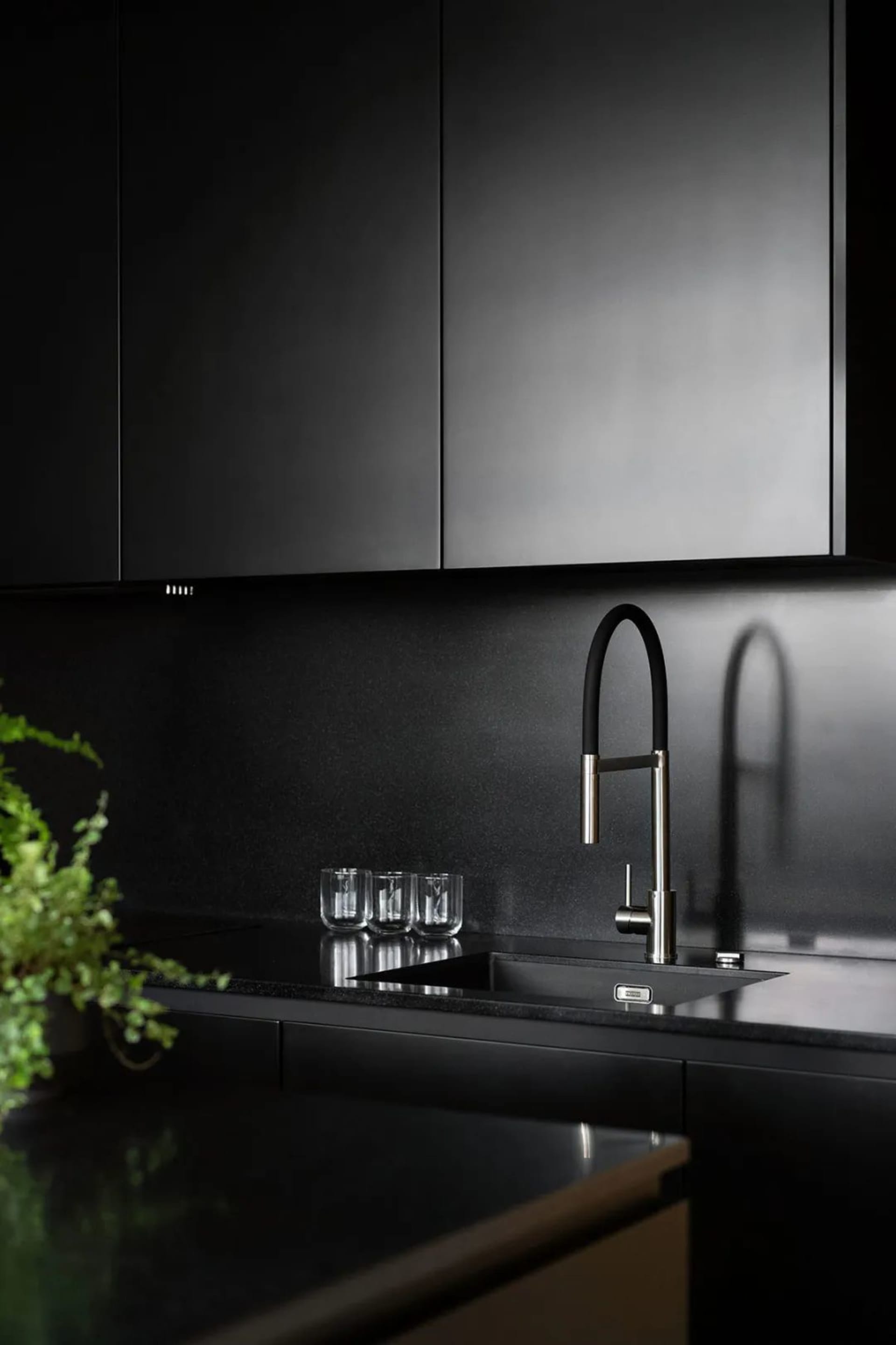 A modern kitchen with black granite countertops and cabinets.