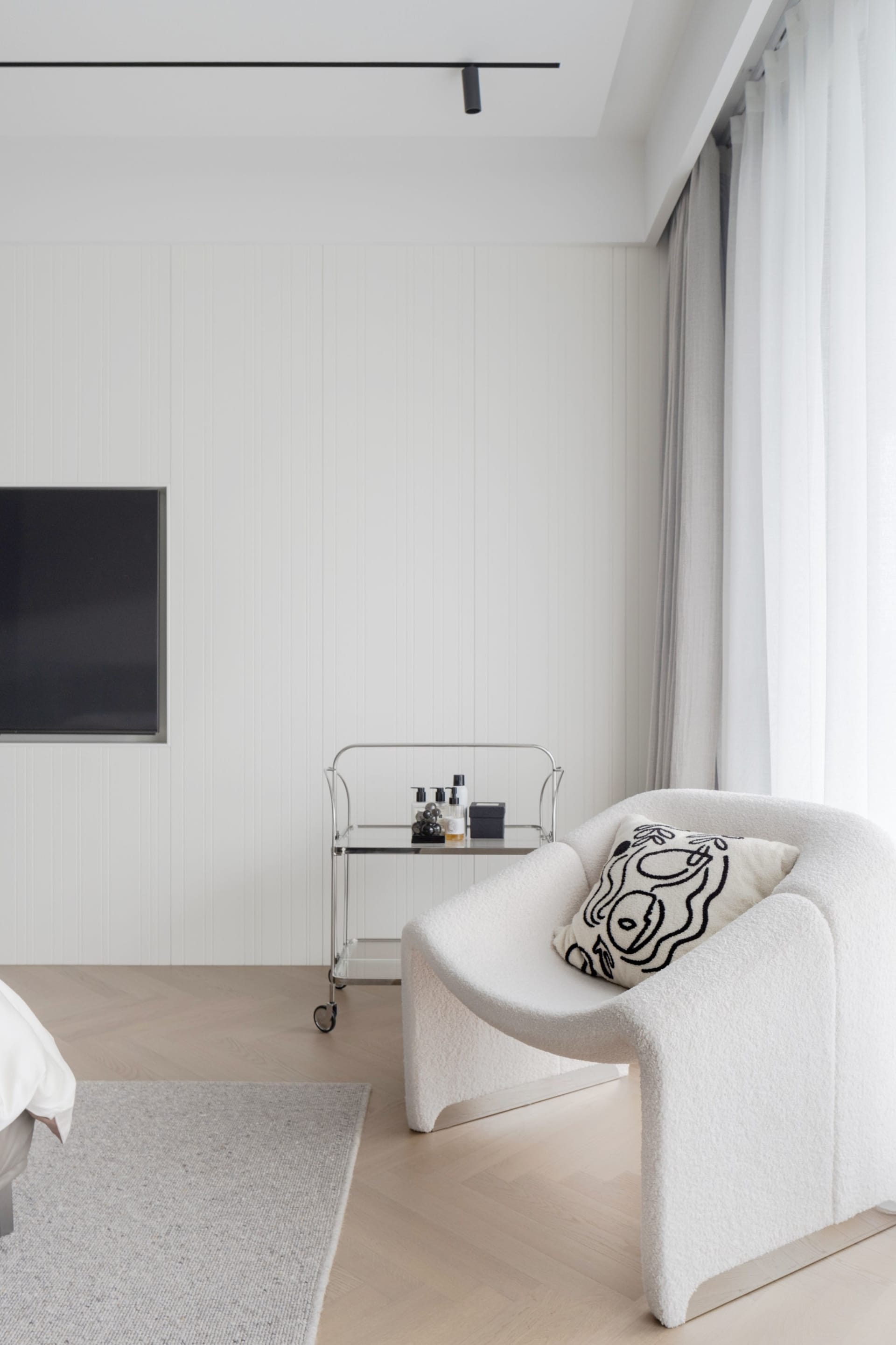 Modern minimalist bedroom with a textured fabric armchair.