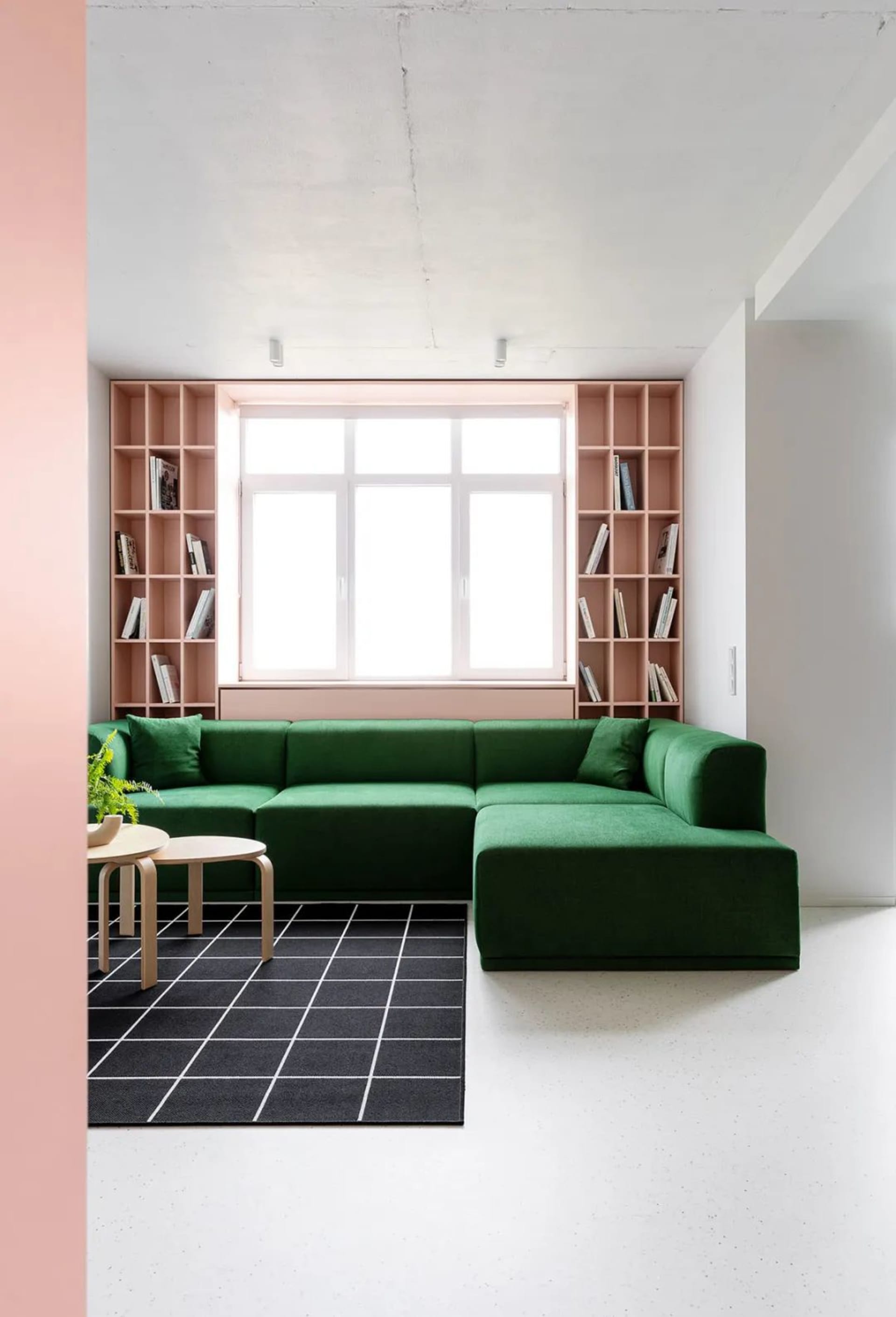 Minimalist living room with a green sofa, bookshelf, and modern furniture