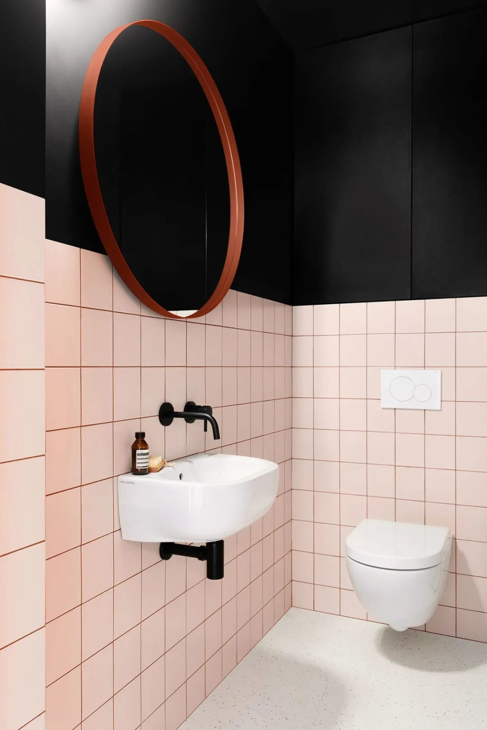 A modern bathroom with pink ceramic tiles and black accents.