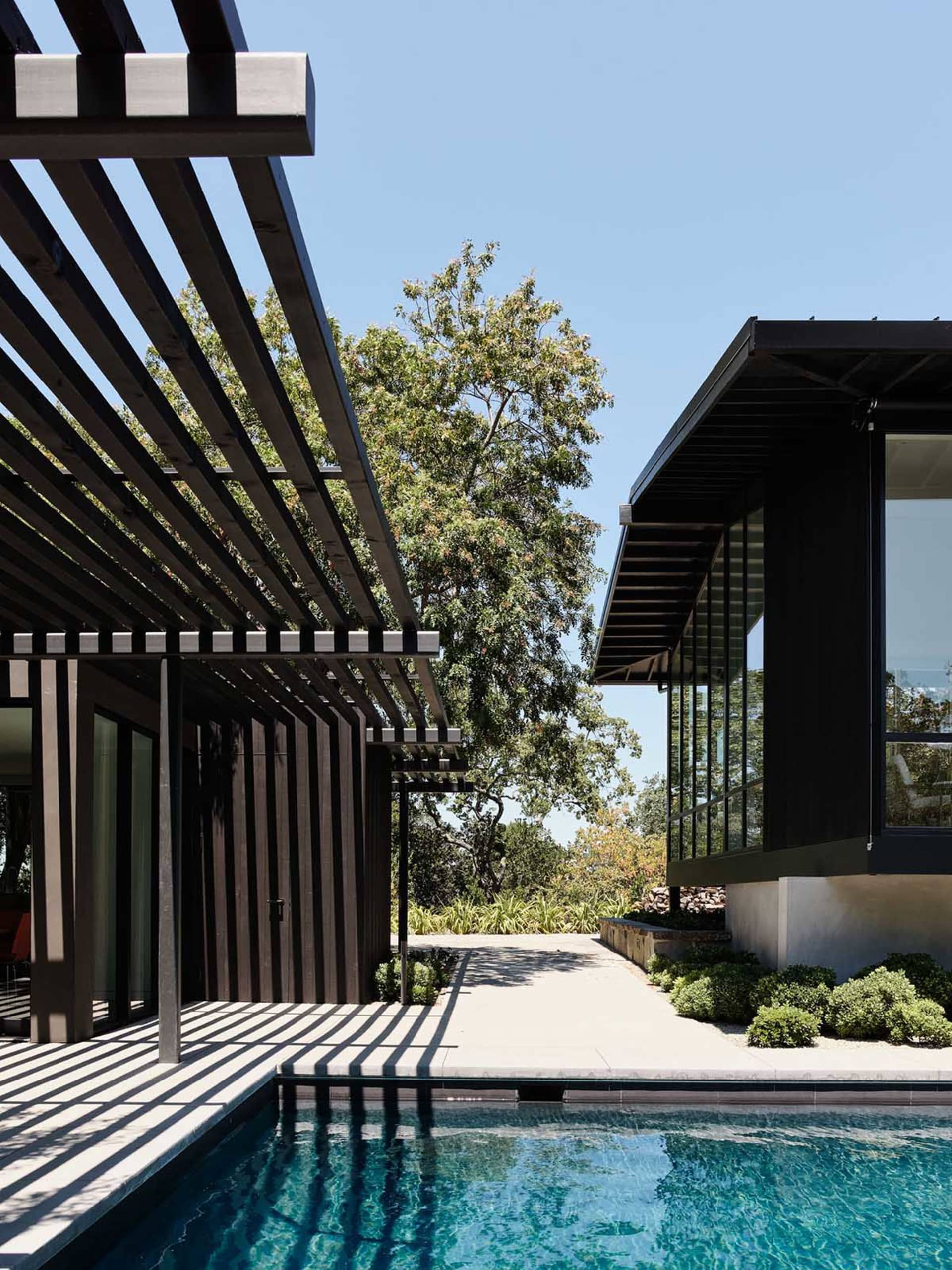 Modern architectural structure featuring black metal elements and a pergola.