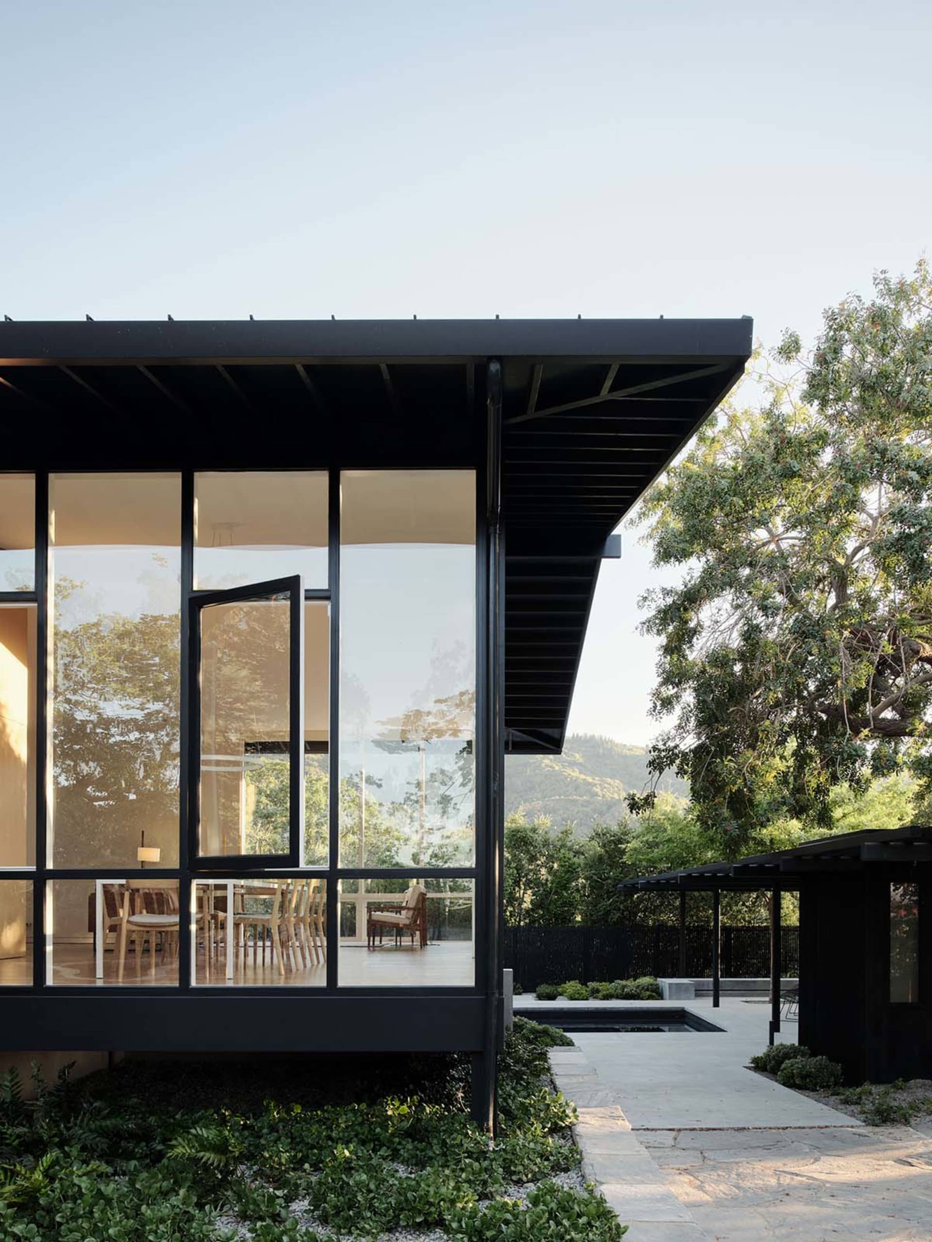 Modern residential exterior featuring large glass panels and metal structural elements.