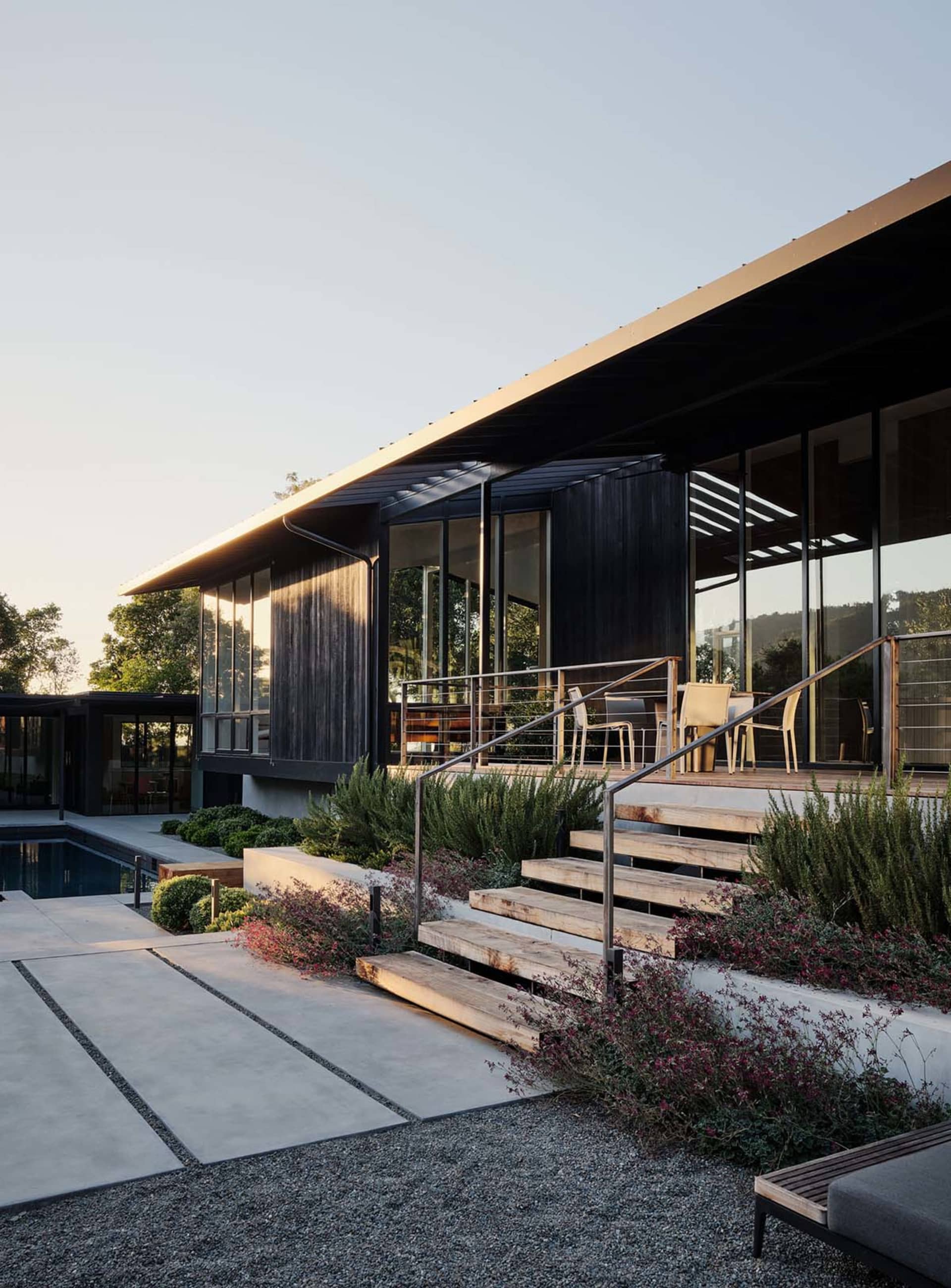 Modern residential exterior featuring wood, glass, and concrete materials with a terrace.
