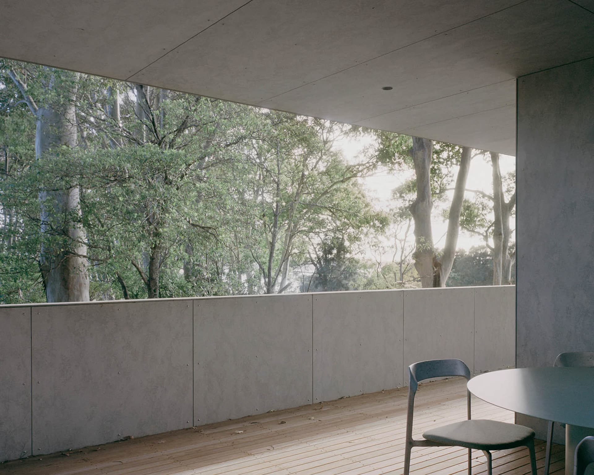 A modern architectural space with concrete walls and a view of trees.