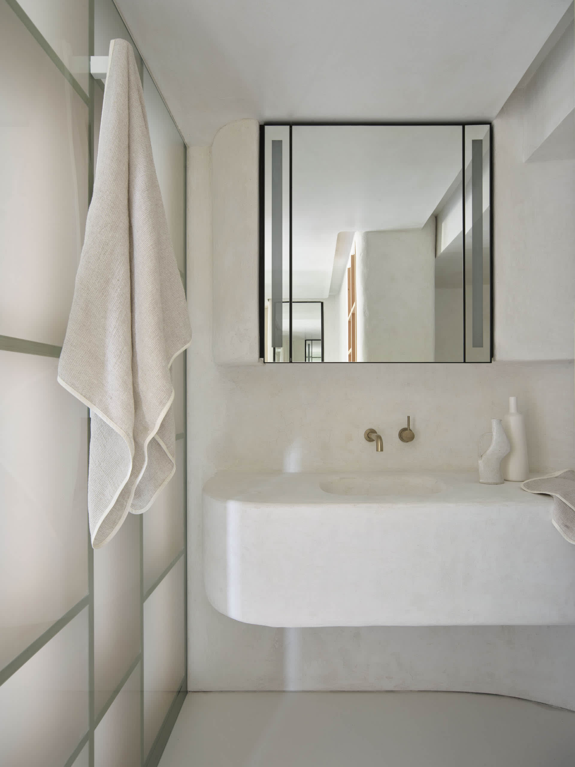 A minimalist bathroom with a concrete sink and a large mirror above it.