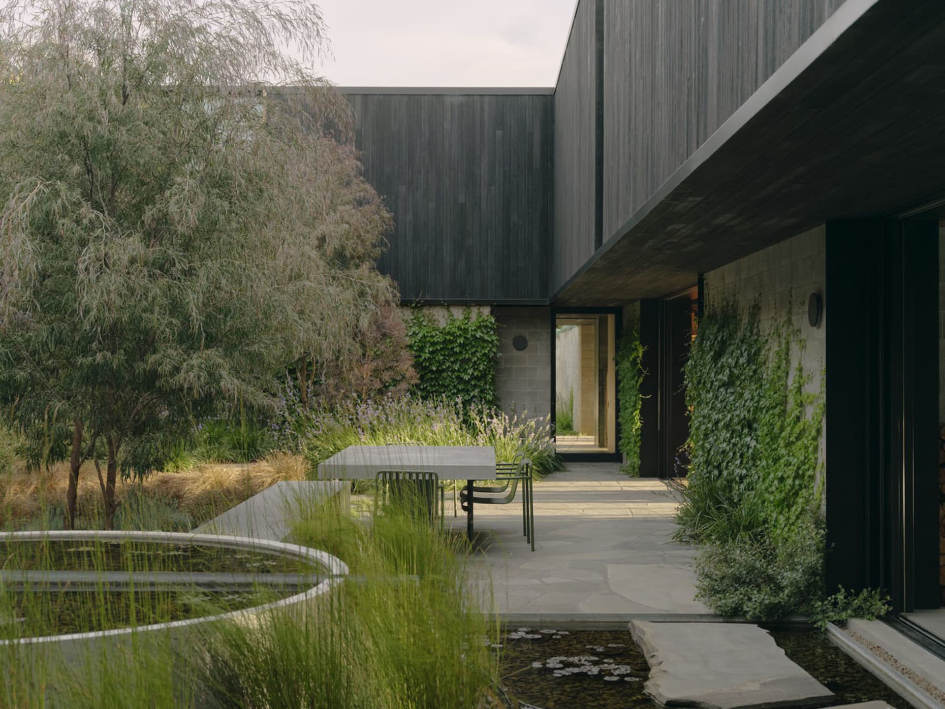 Modern backyard featuring wooden furniture and concrete pavers.