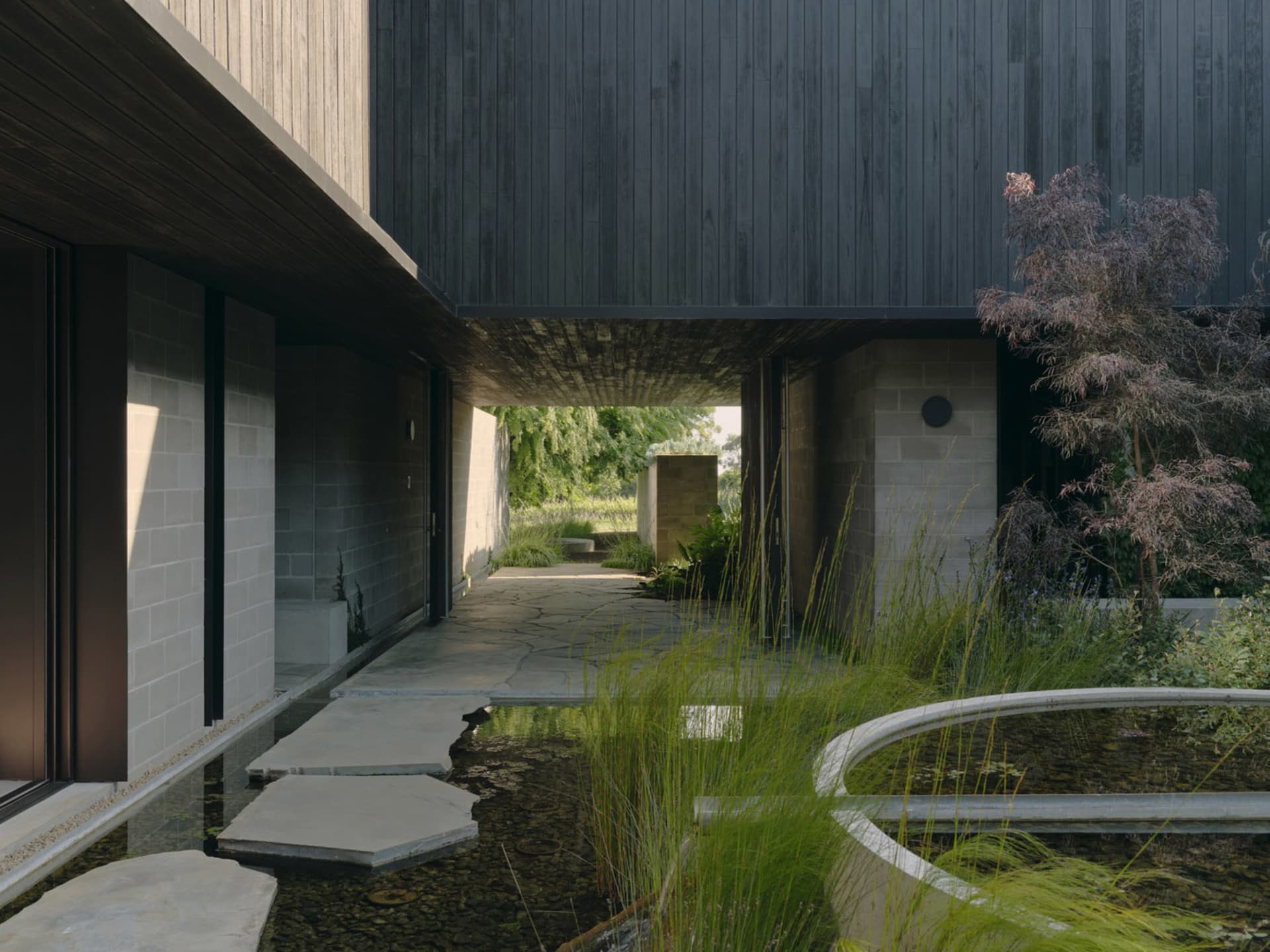 A modern residential entryway featuring a black panel wall, concrete steps, and a water feature.