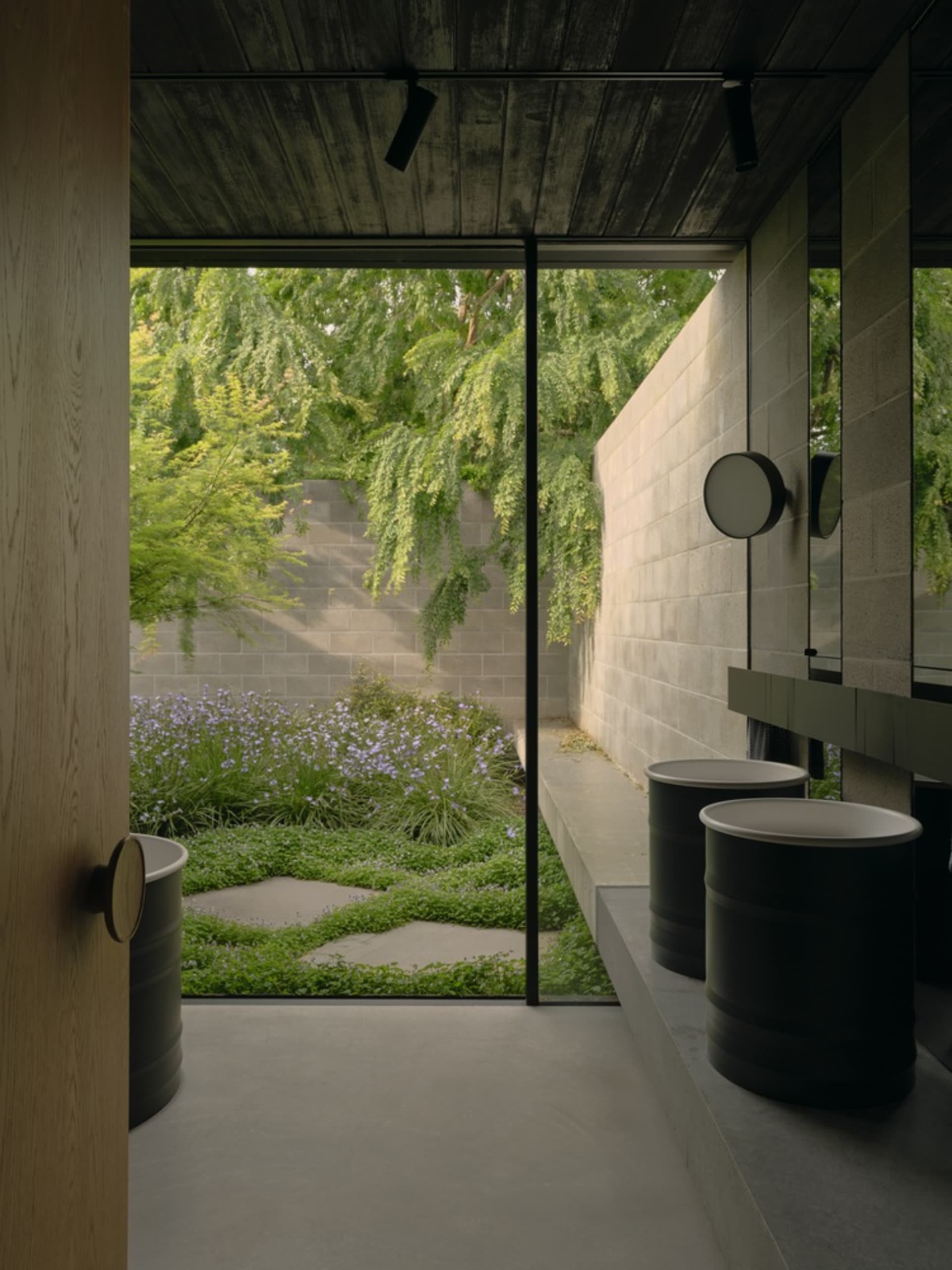 Modern gray bathroom interior with concrete materials and an outdoor view of greenery.