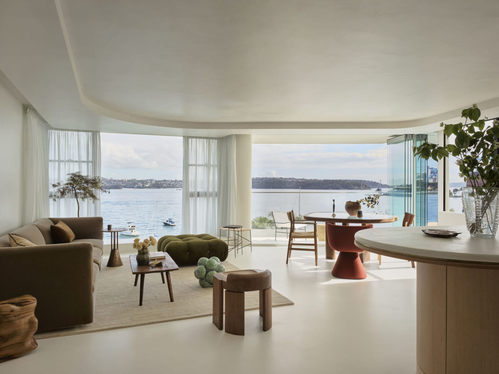 Modern living room with panoramic ocean view, featuring minimalist furniture and contemporary decor elements.