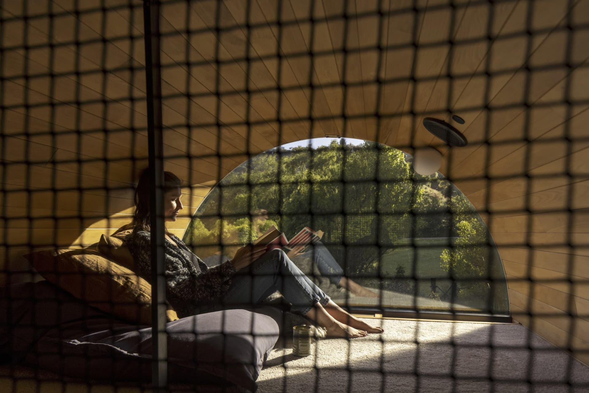 A person reading a book in a modern interior with wooden walls and a curved window.