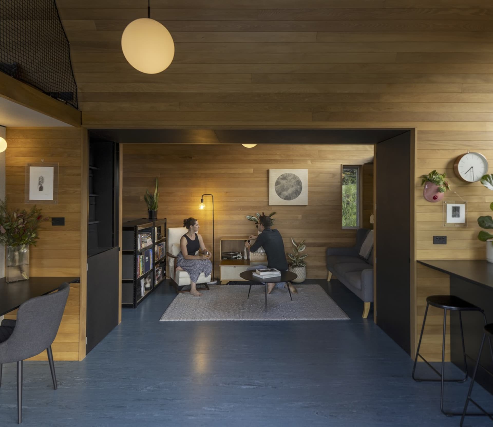 A modern living room featuring wood flooring and wood-paneled walls.
