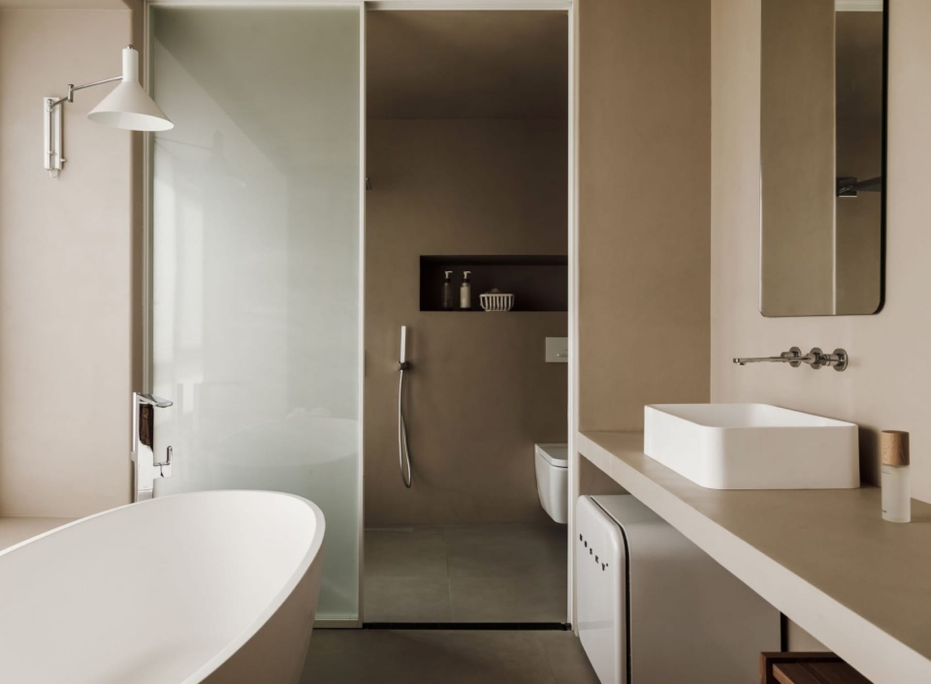 Minimalist bathroom with a white bathtub, concrete walls, and a floating vanity with a white sink.