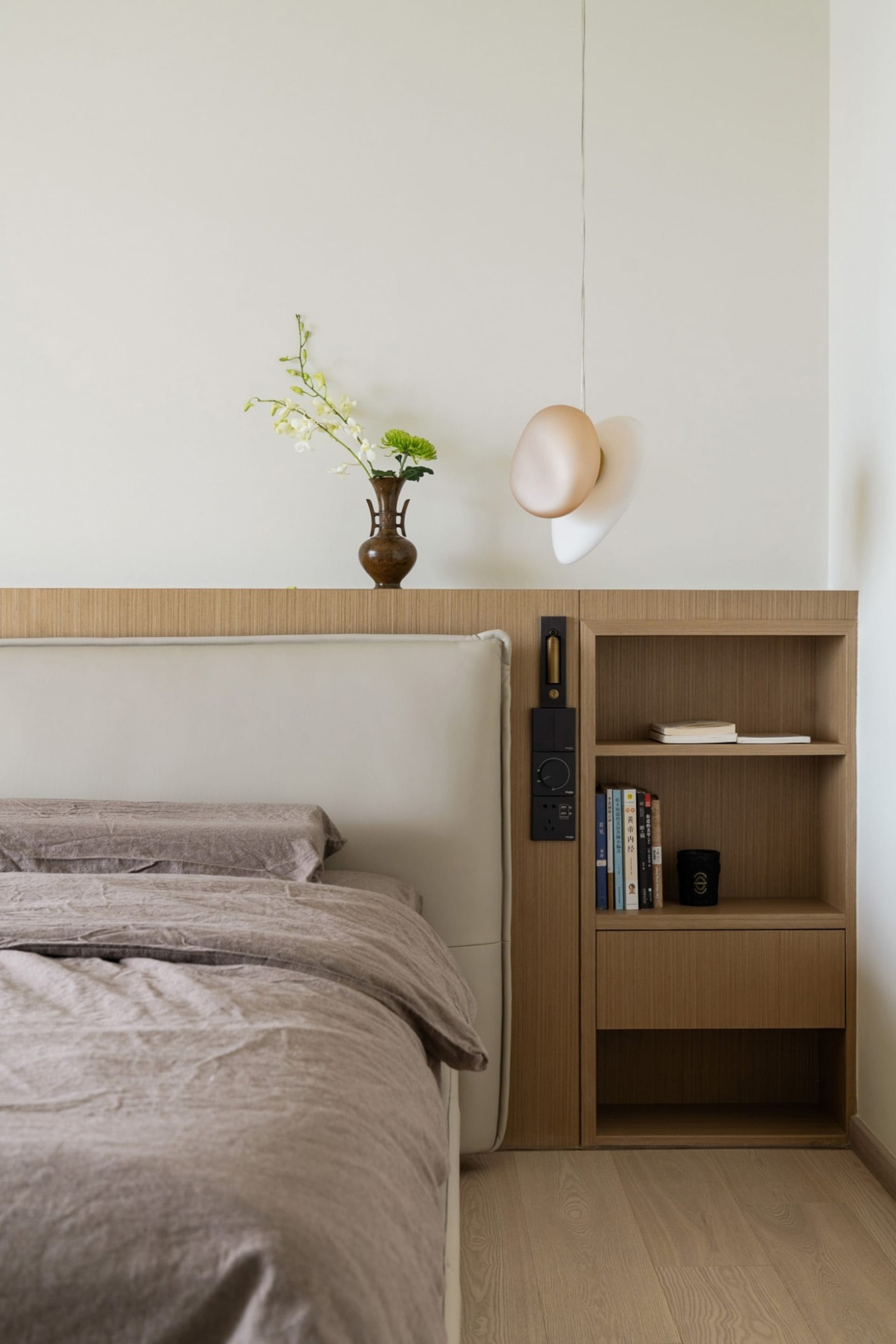 Modern, minimalist bedroom featuring wooden furniture and a vase with orchids.
