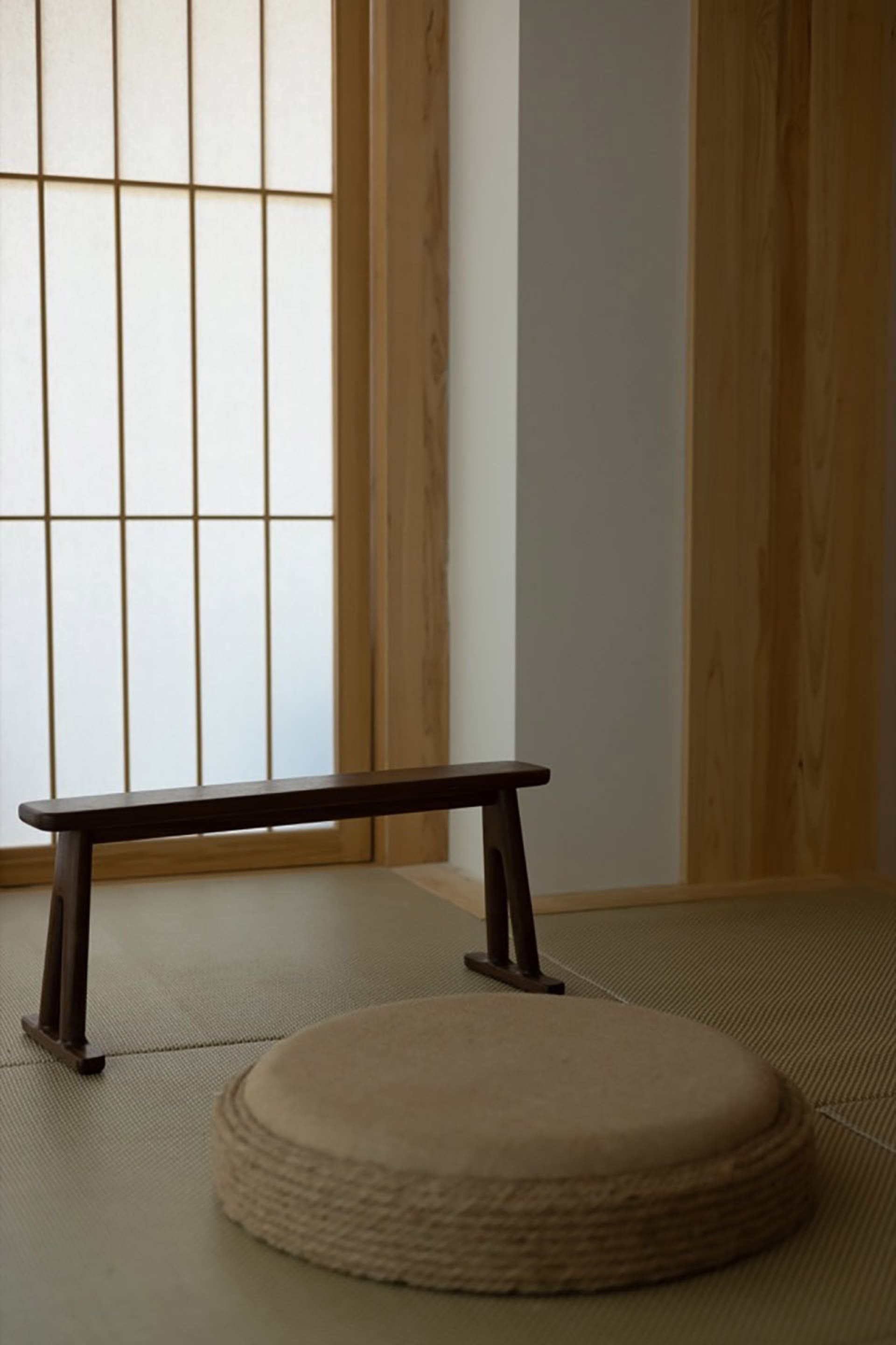 傳統木製浮動凳與長椅，搭配紙地板，置於極簡室內空間。