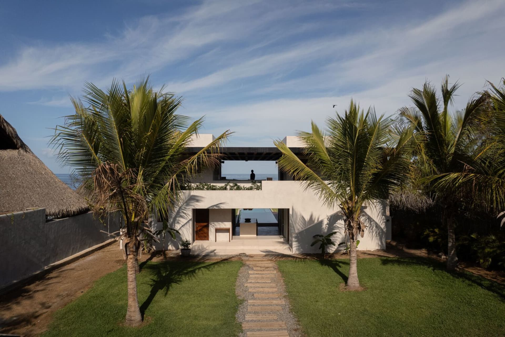 A modern residential house with a concrete exterior and a green lawn.