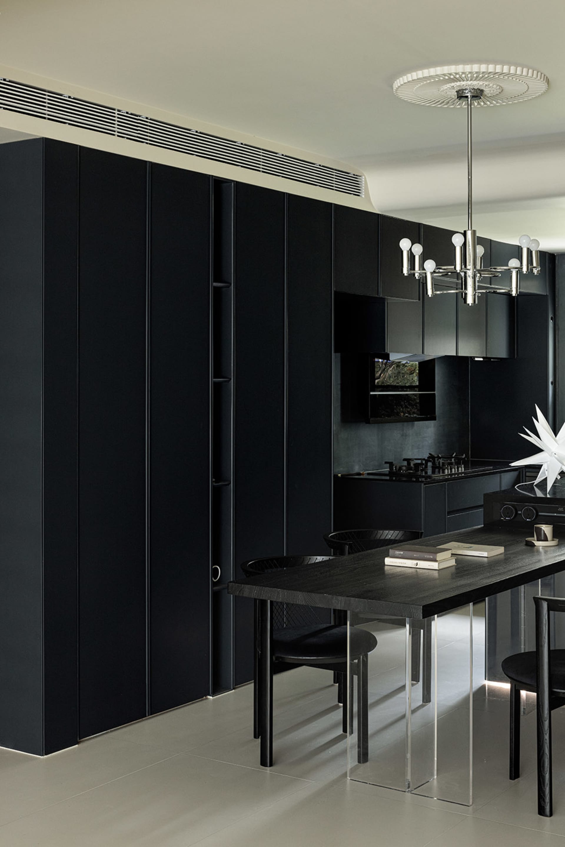 A modern kitchen with black cabinets and a long table.