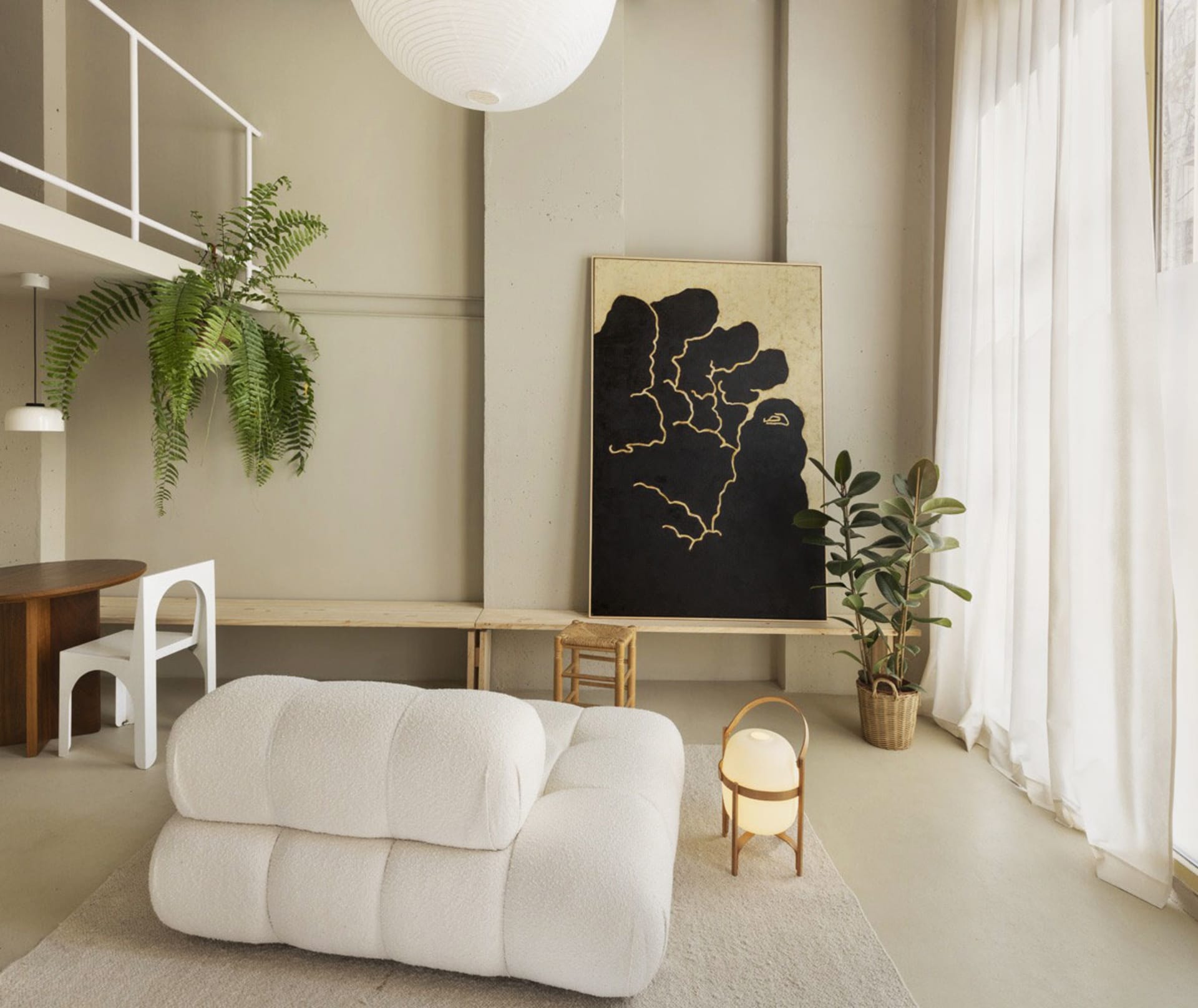 A modern living room with neutral tones, featuring plush seating, artistic wall decor, and indoor plants.