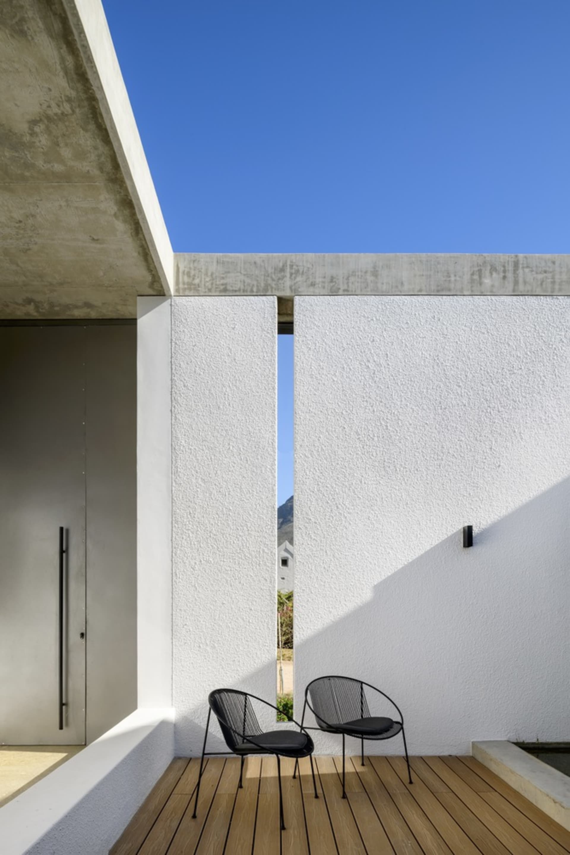 Modern patio with concrete walls and black wire chairs.
