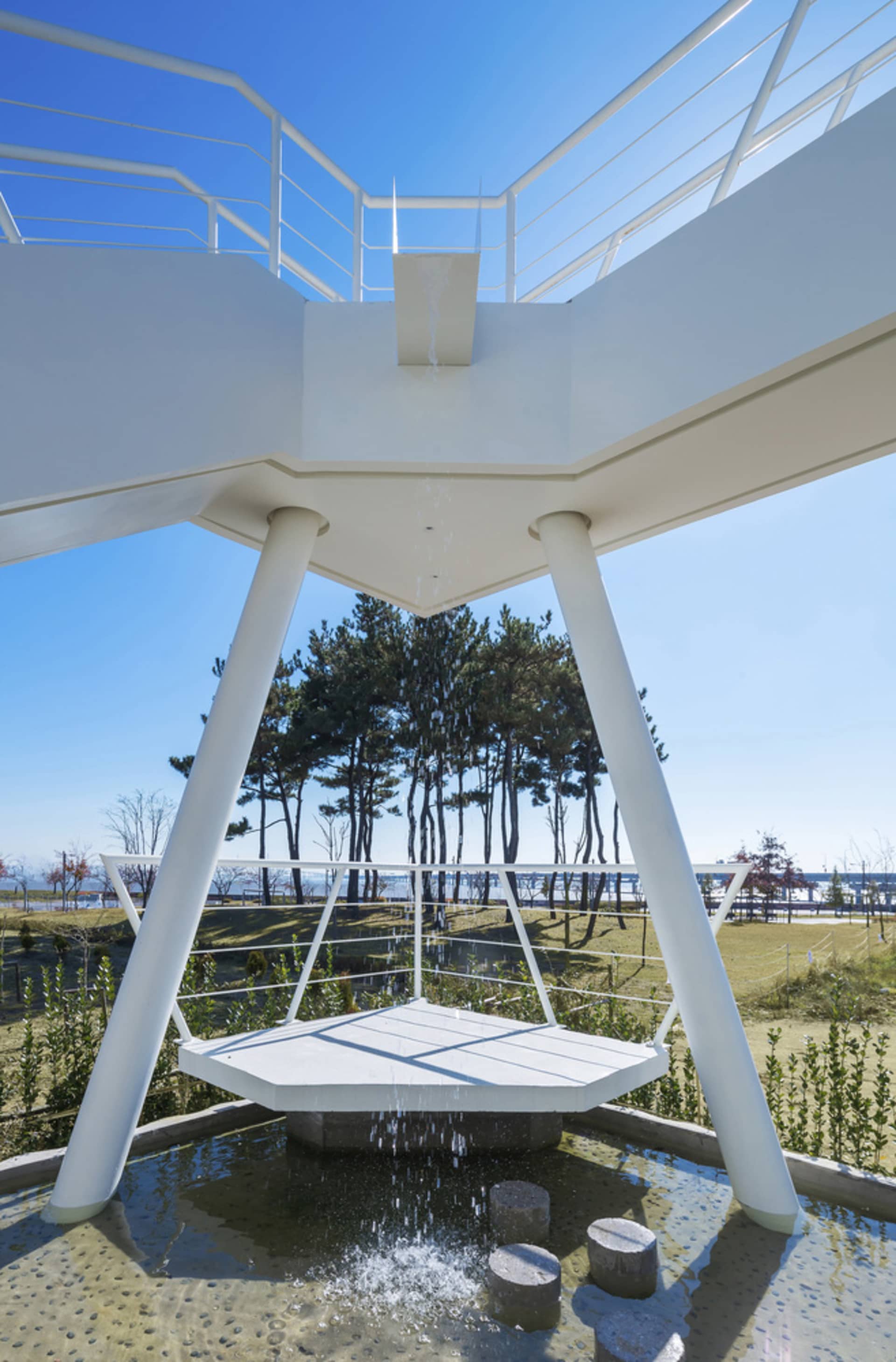 A minimalist metal public space with water features and a seating area.