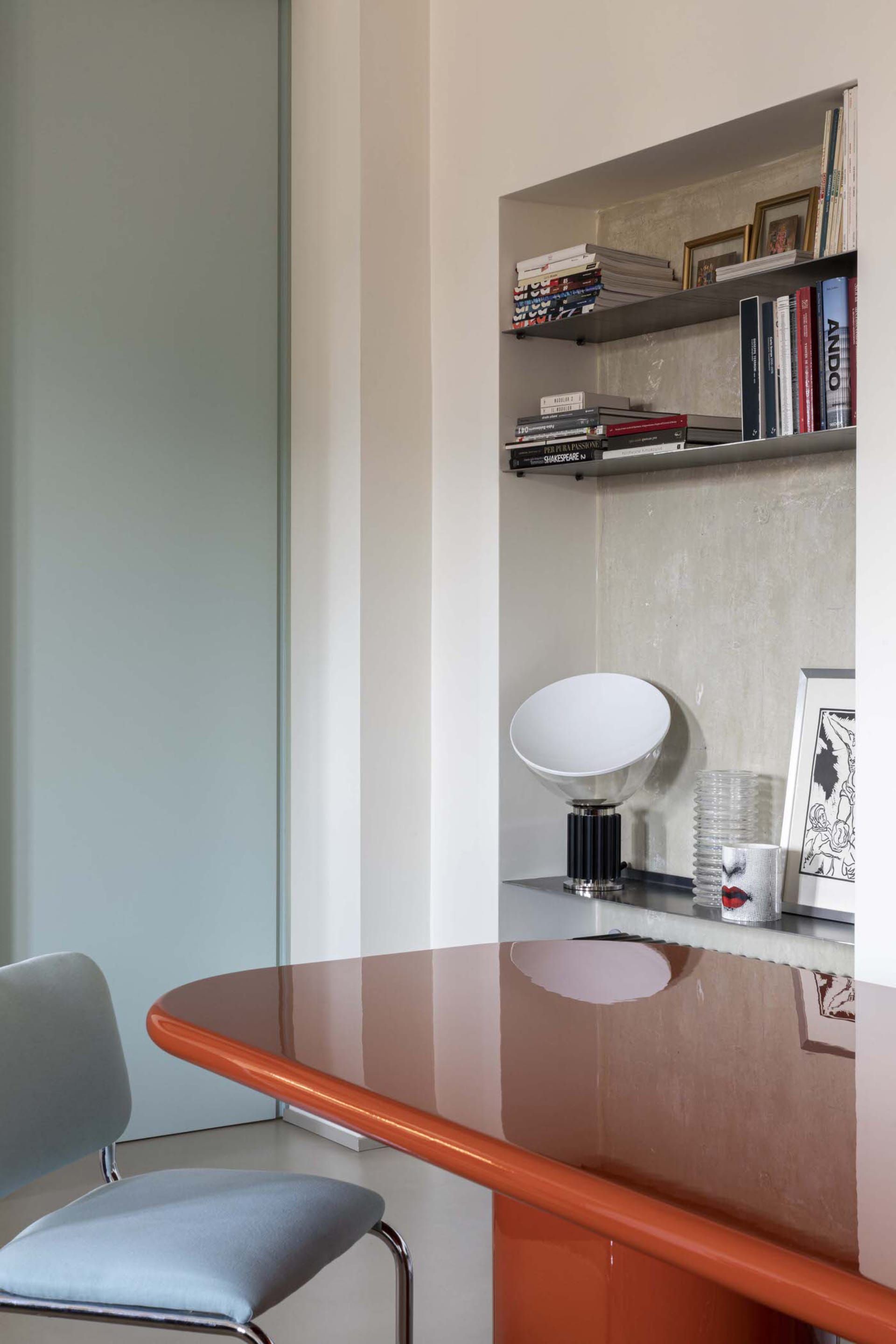 Minimalist dining room featuring a glass and metal table and light blue chair.
