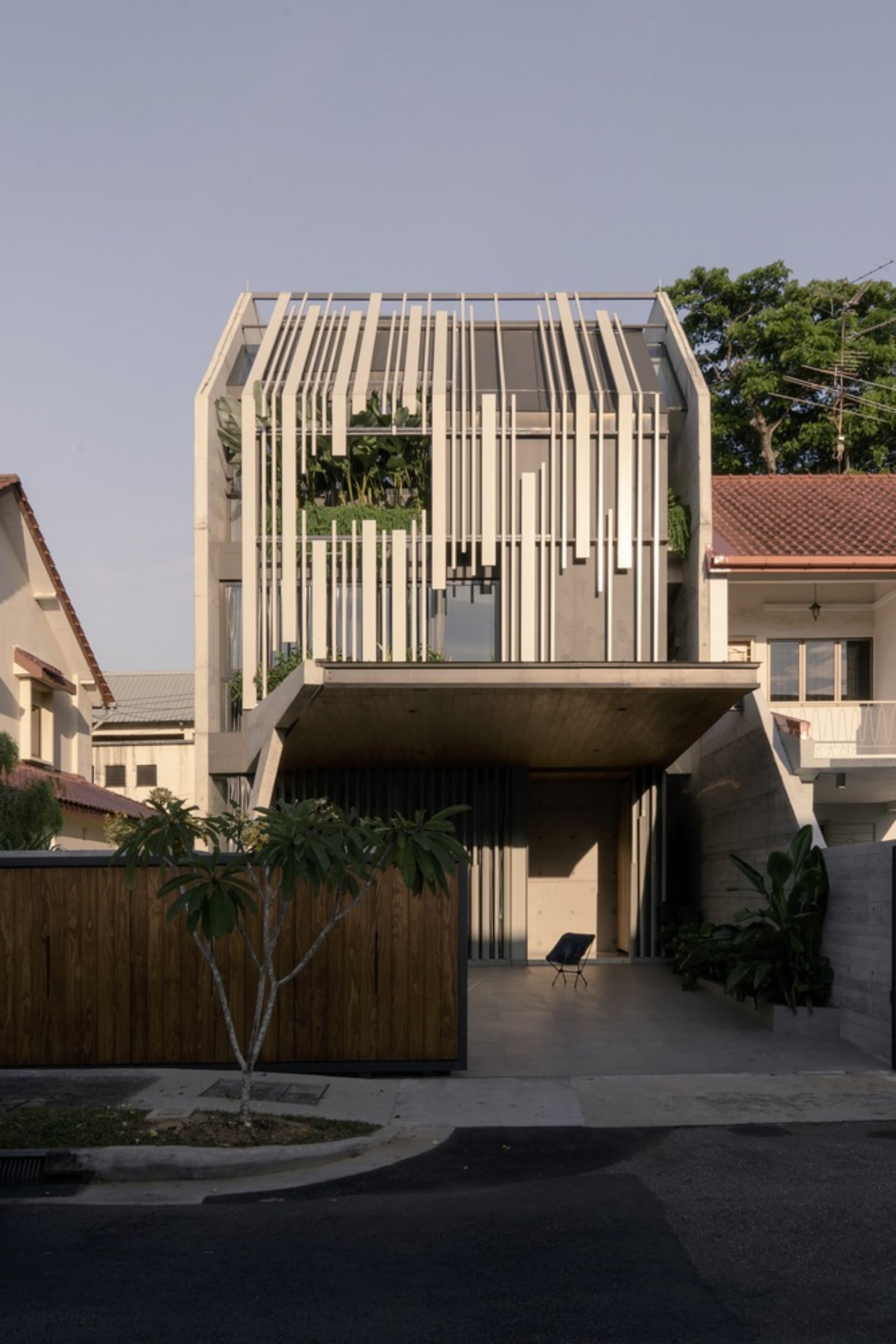A modern house with a concrete and glass exterior, featuring a patio area with a chair.