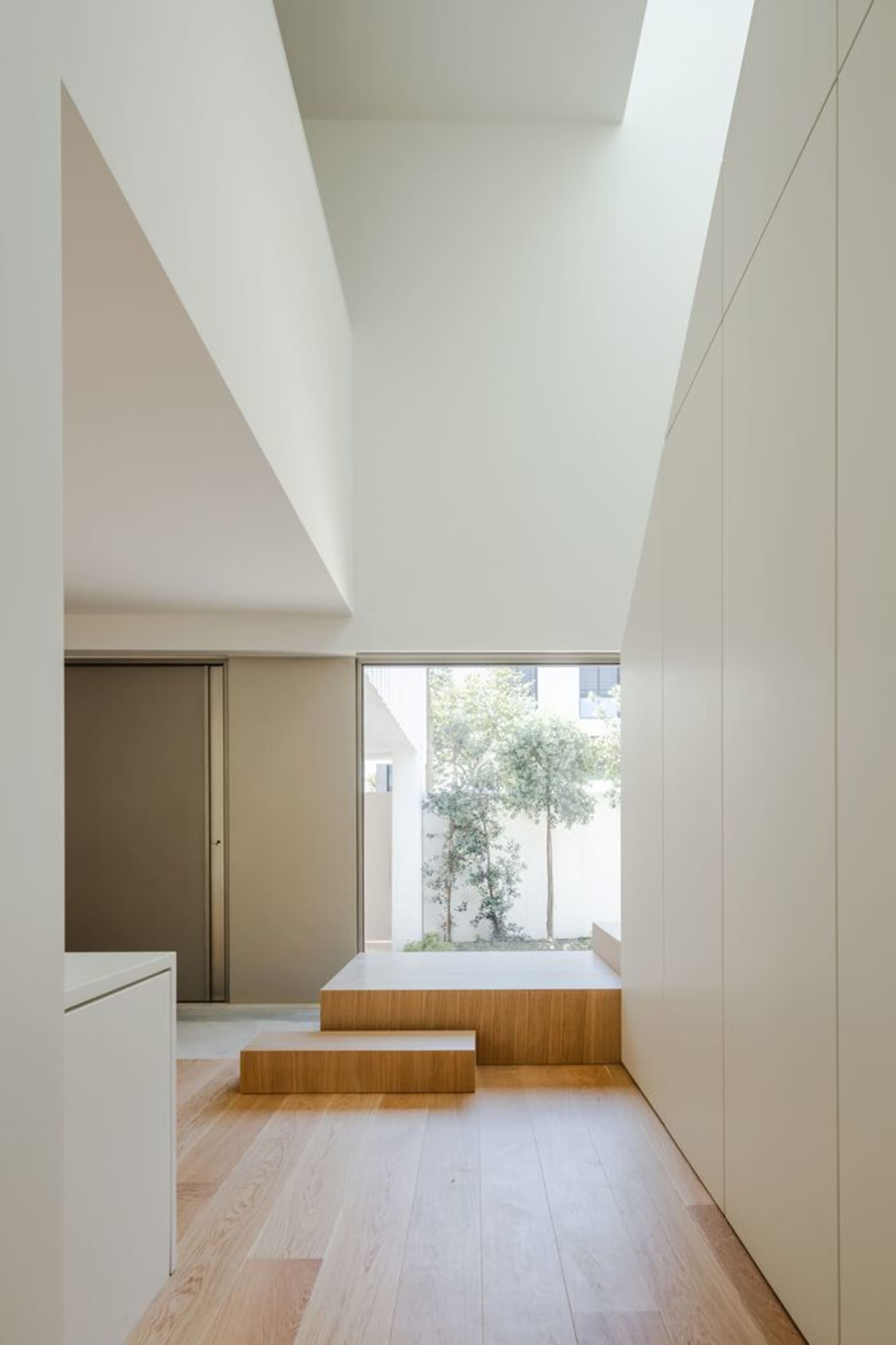 Modern residential hallway with white walls and wooden flooring.