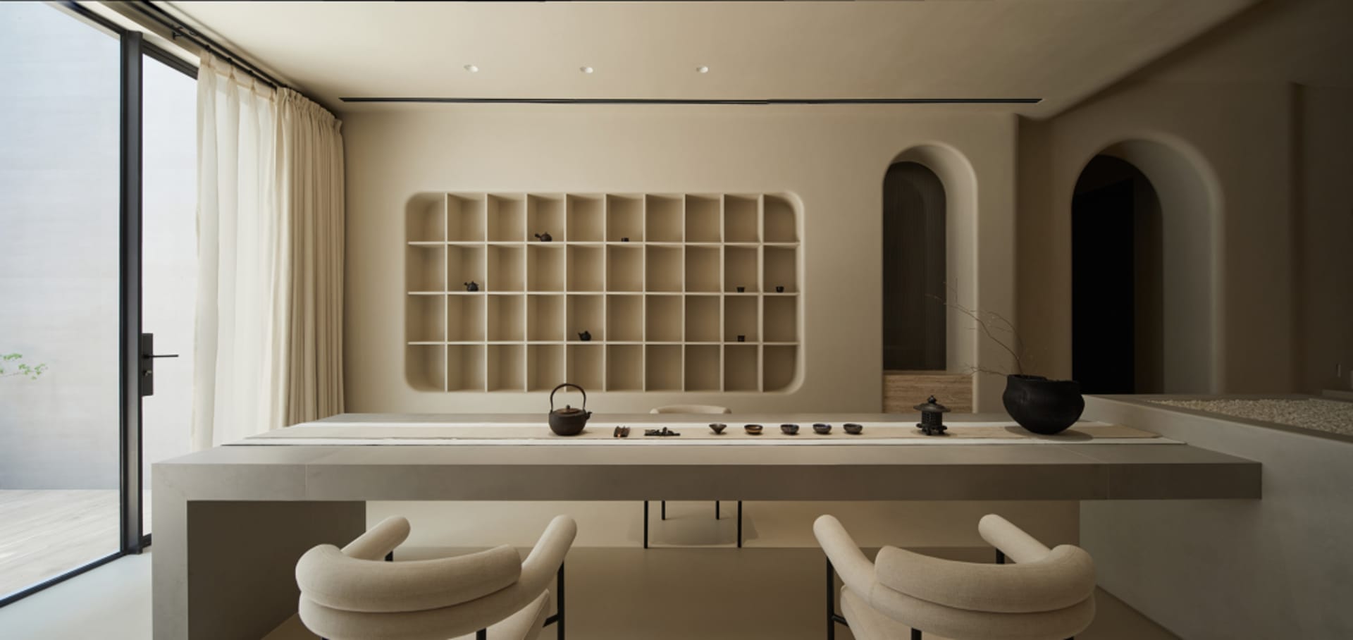 現代餐廳融合混凝土與木質元素,長桌搭配簡約餐具,並有拱形門框