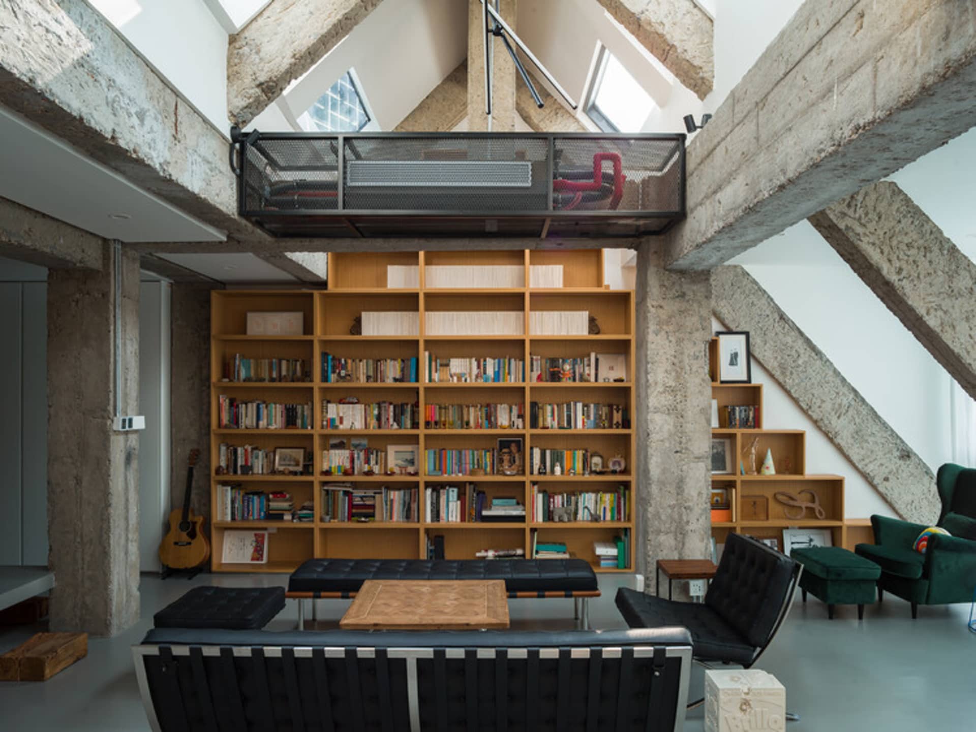 Industrial living room with concrete walls, wooden furniture, metal accents, and a large bookshelf.